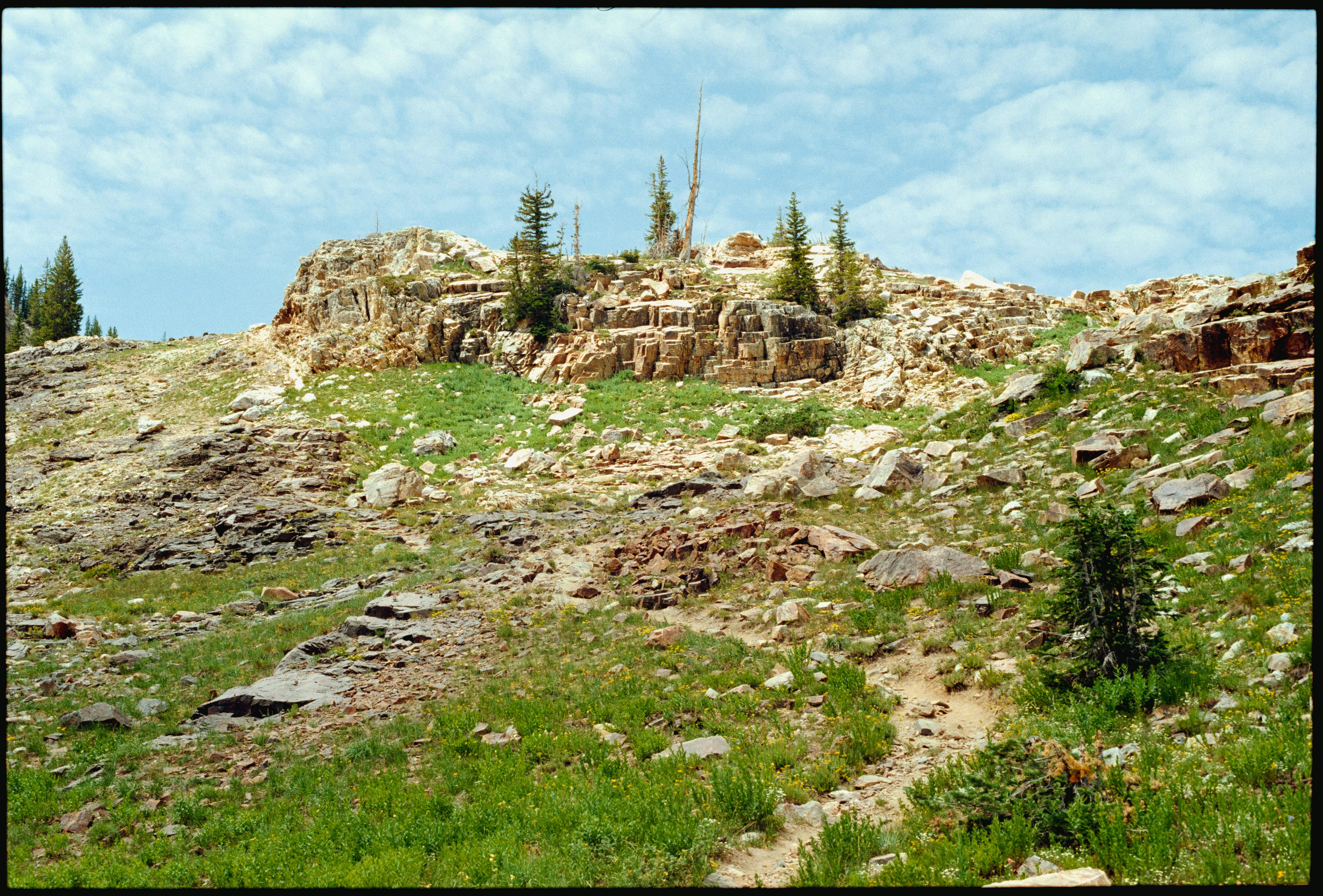 A dirt path winding up a rocky, grassy mountain slope