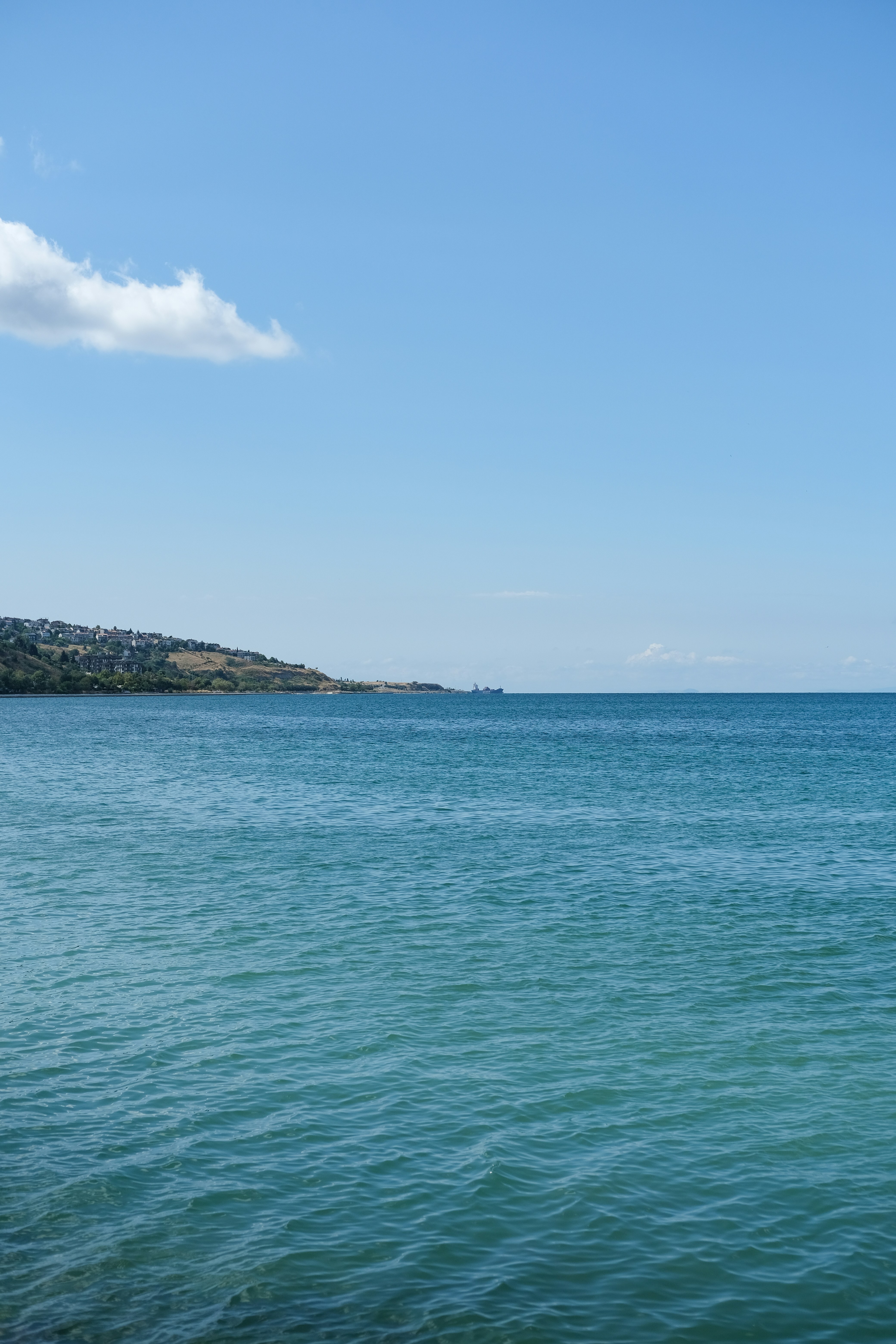 Océan bleu calme sous un ciel clair, côte lointaine