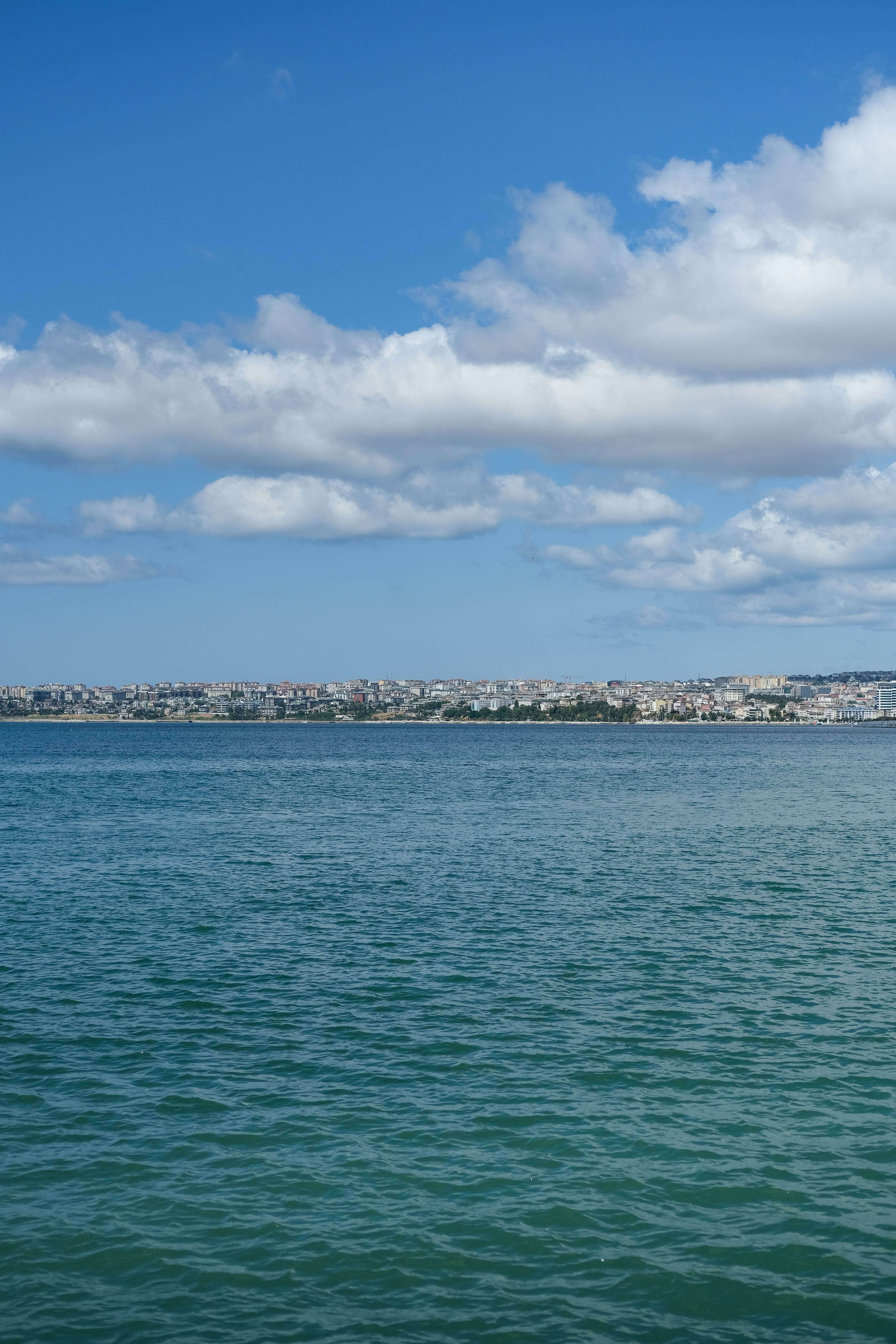 La ligne d’horizon de la ville traverse des eaux bleues sous un ciel nuageux