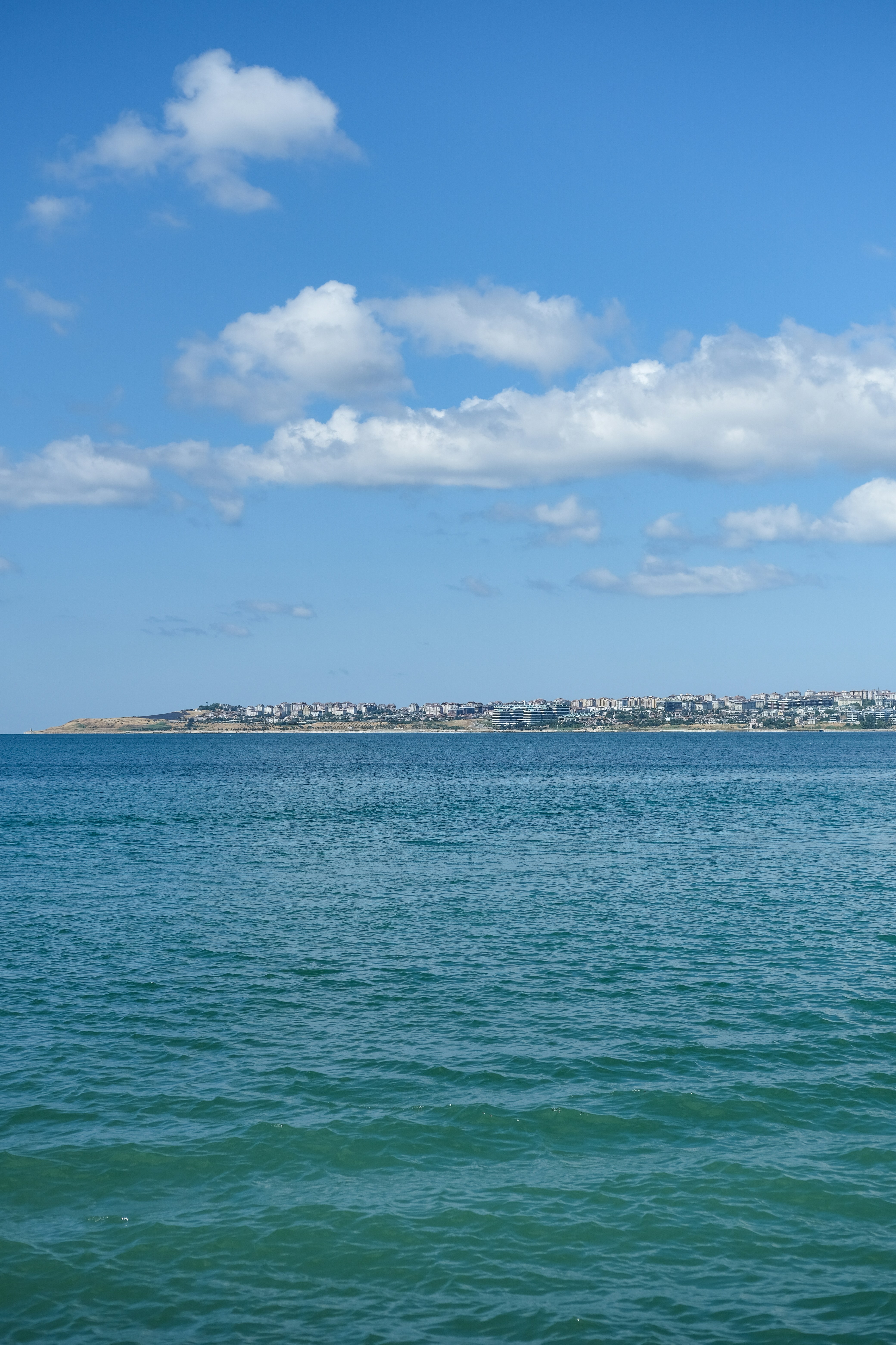 Océan avec une ville côtière lointaine sous un ciel bleu