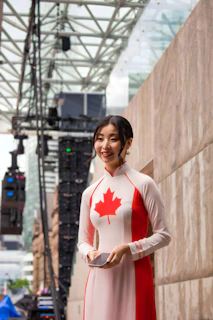A woman in a canadian-themed ao dai stands outdoors.