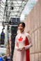 A woman in a canadian-themed ao dai stands outdoors.