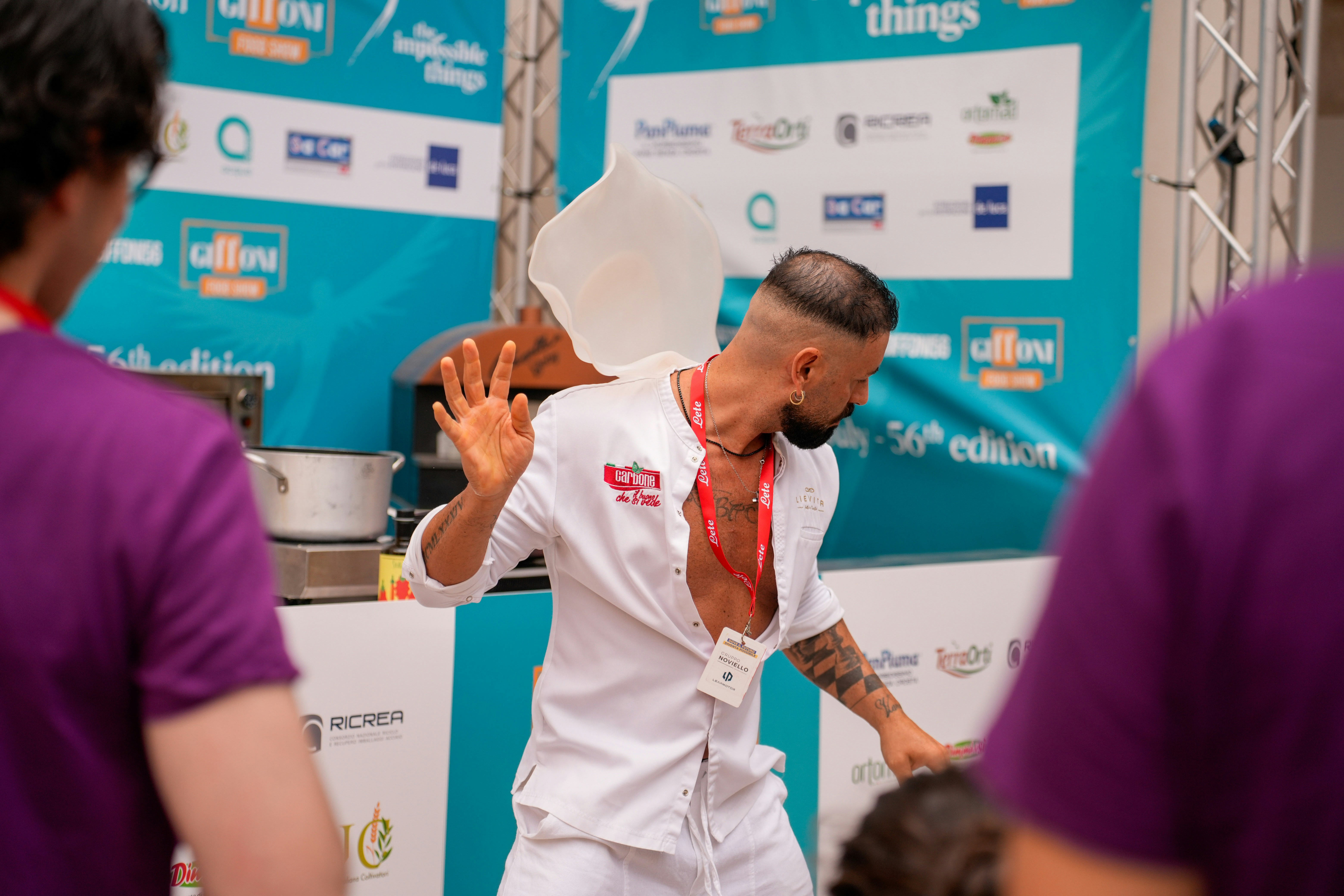 Chef tossing pizza dough at an indoor event.