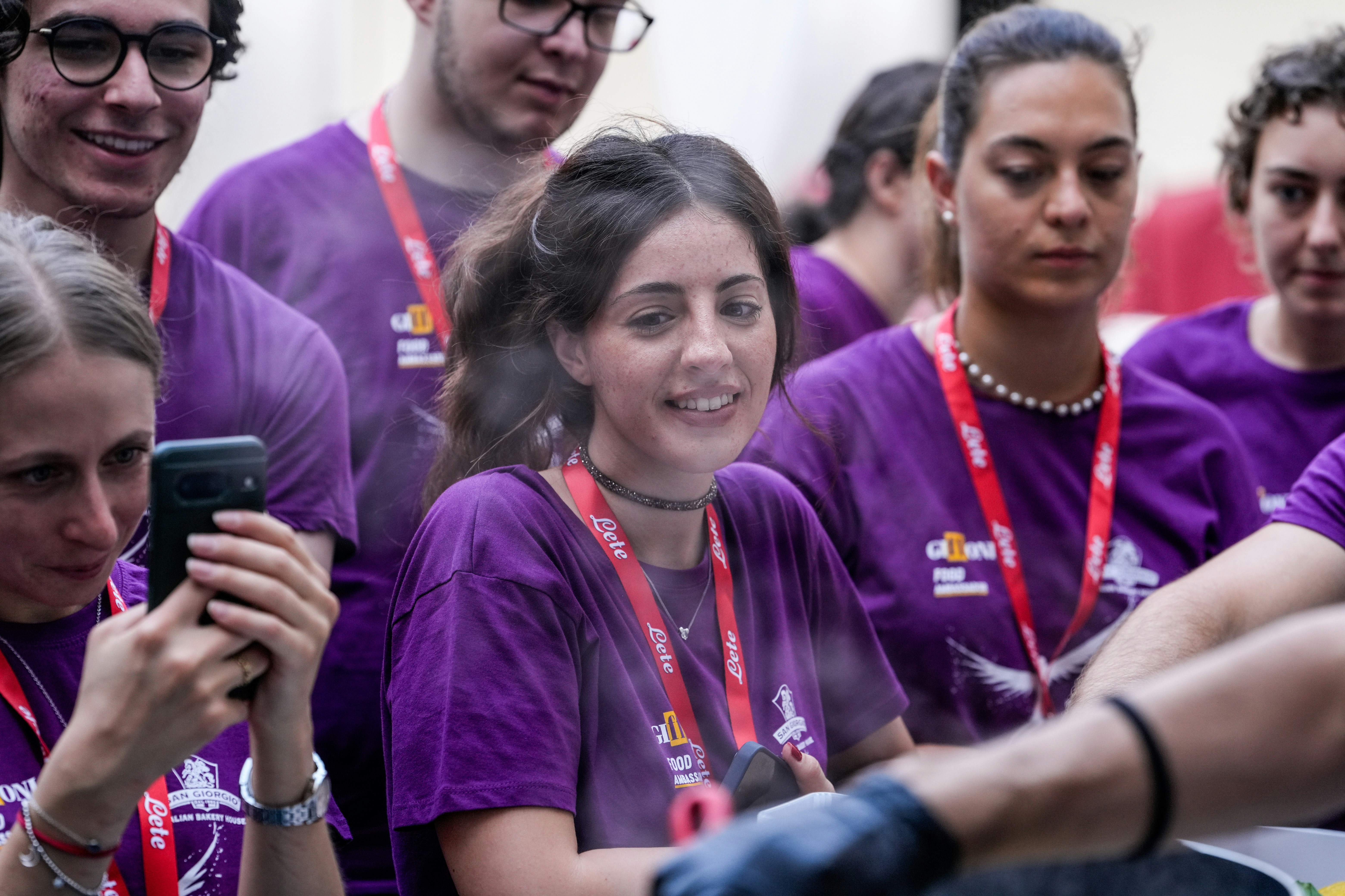 Young people in purple shirts watching an event.