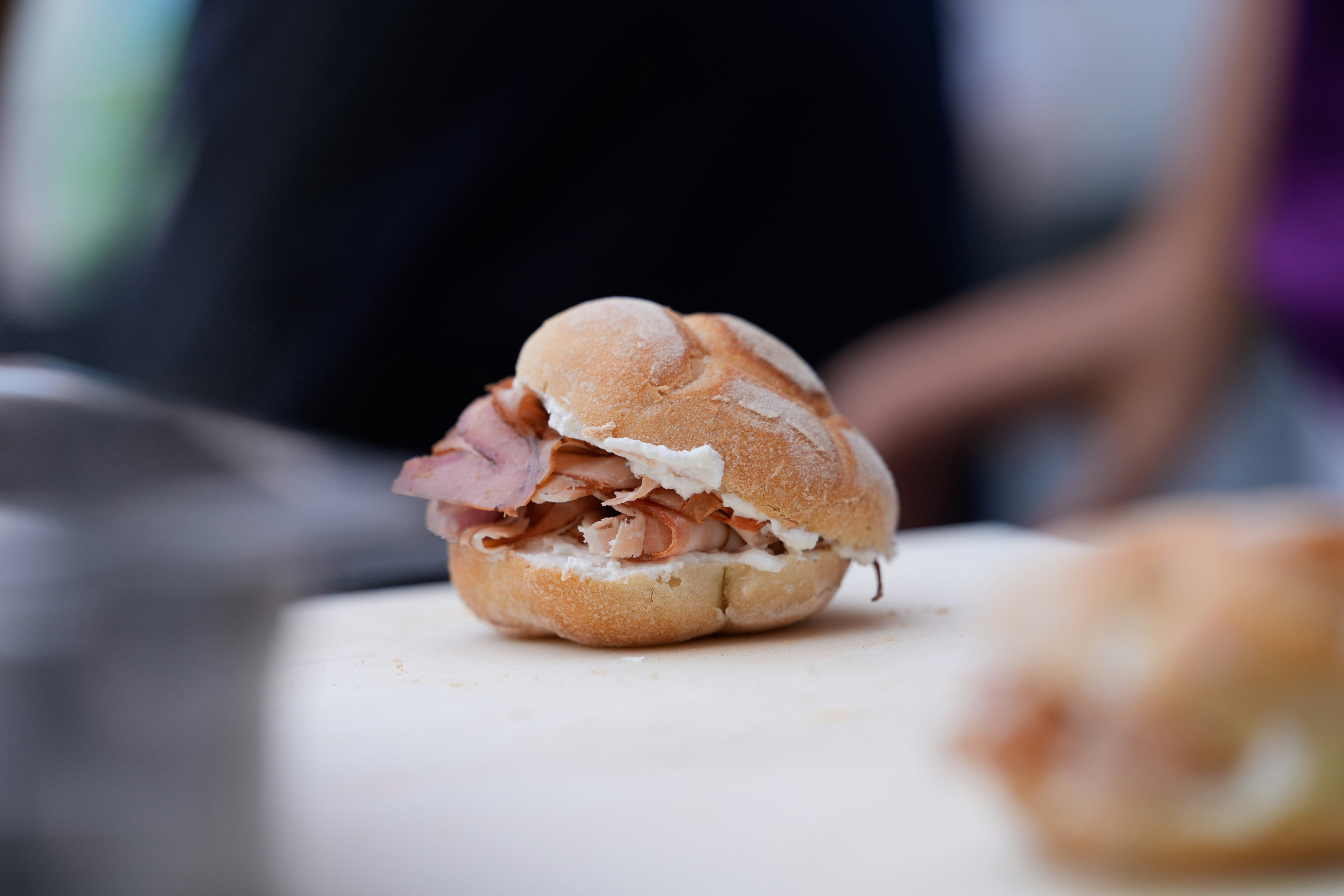 A small bun sandwich with meat and white filling.