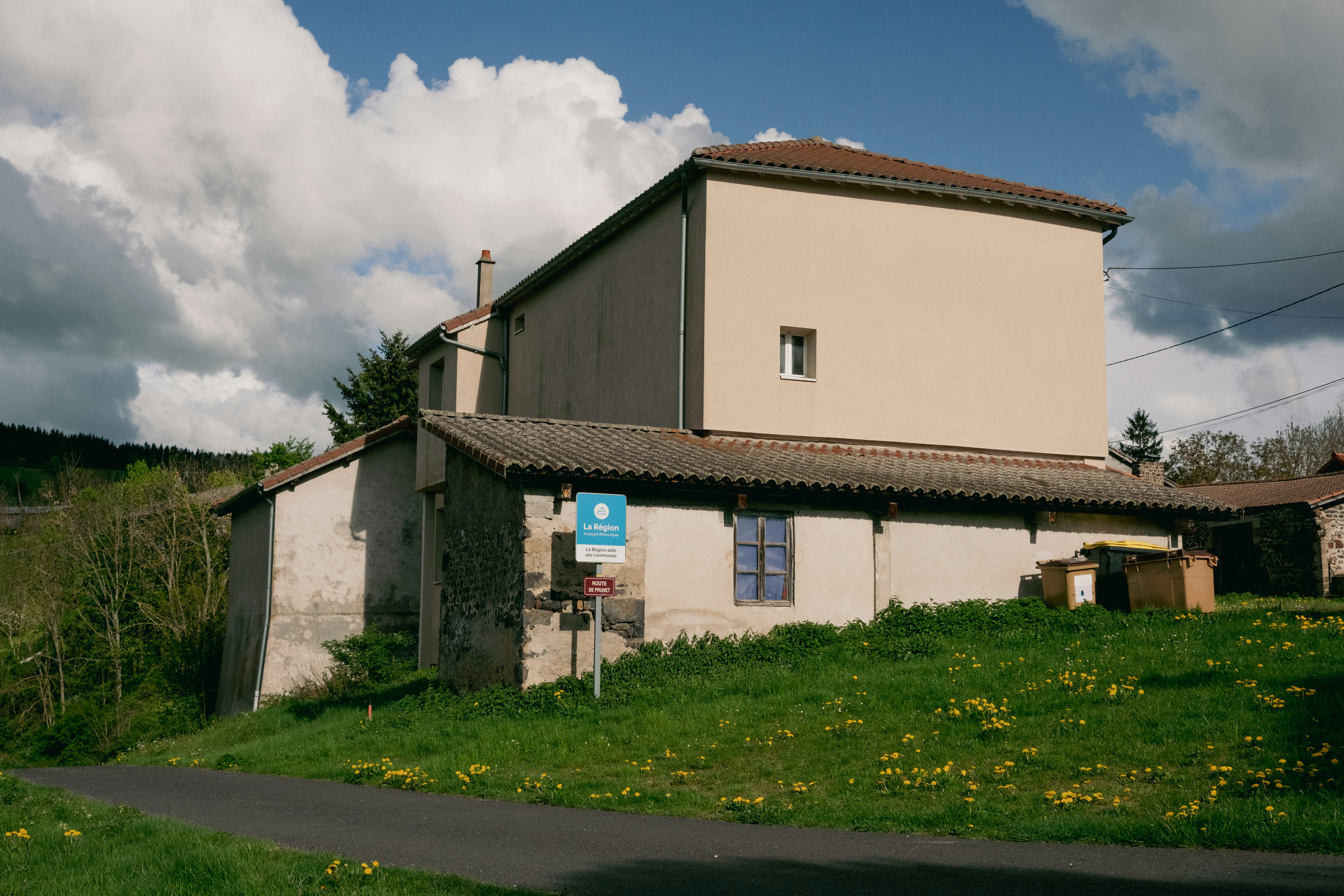 Rural building with green grass and road under cloudy sky