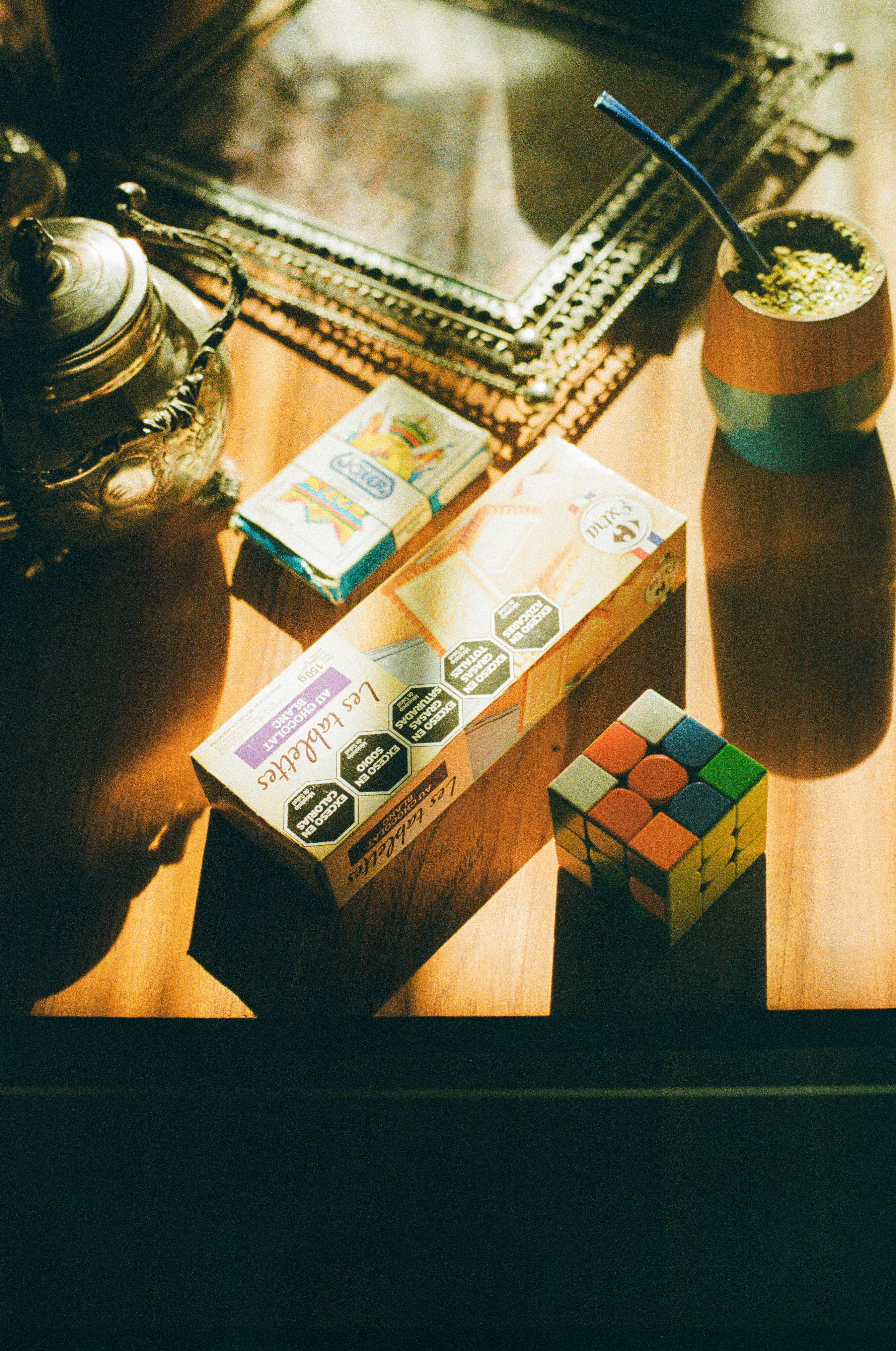 Teapot, mate, rubik's cube, and packages on a sunlit table