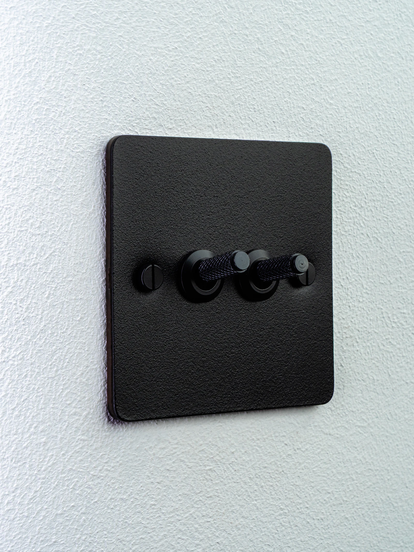 Black double toggle light switch on a white wall