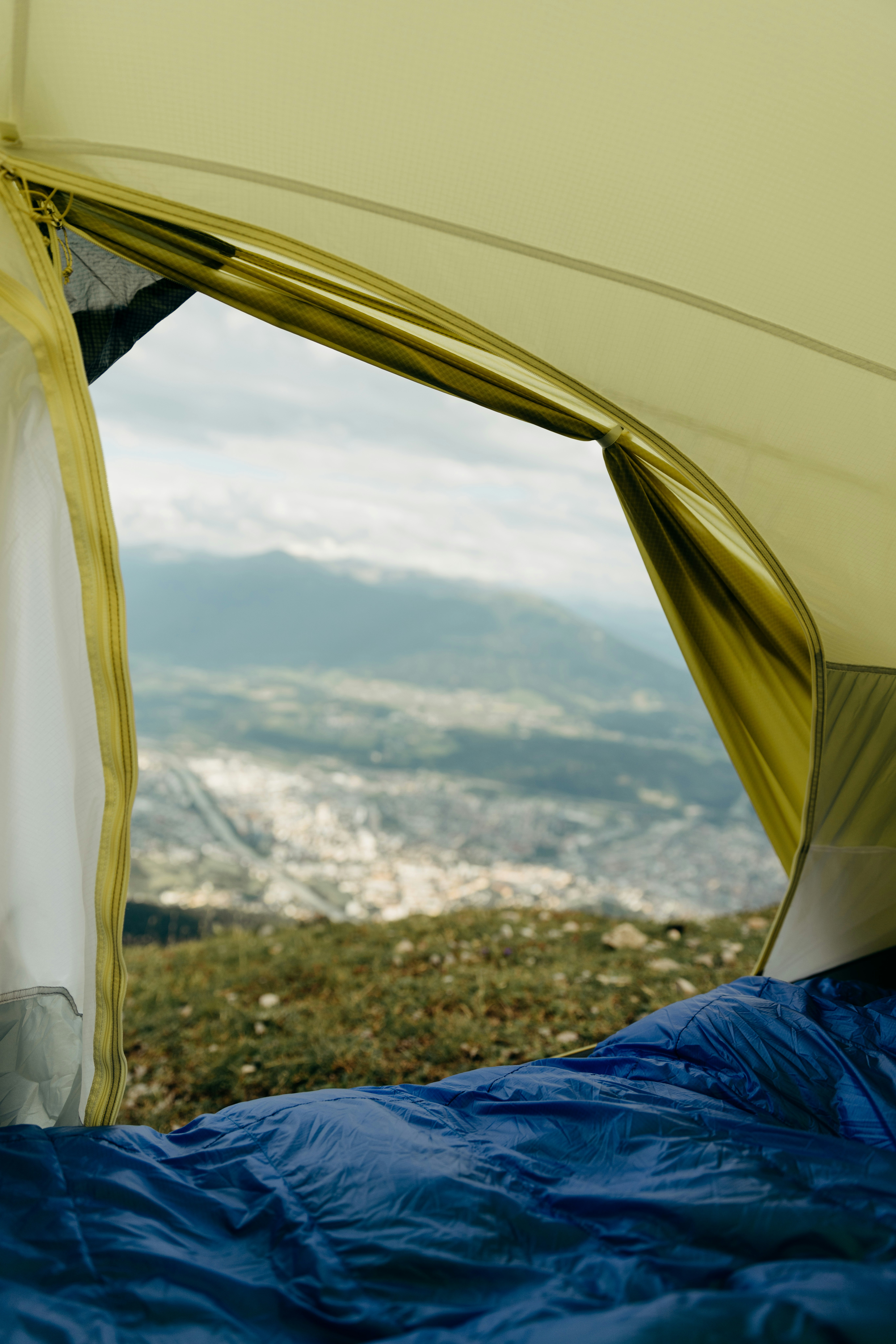 A blue sleeping bag inside an open tent looking out over mountains