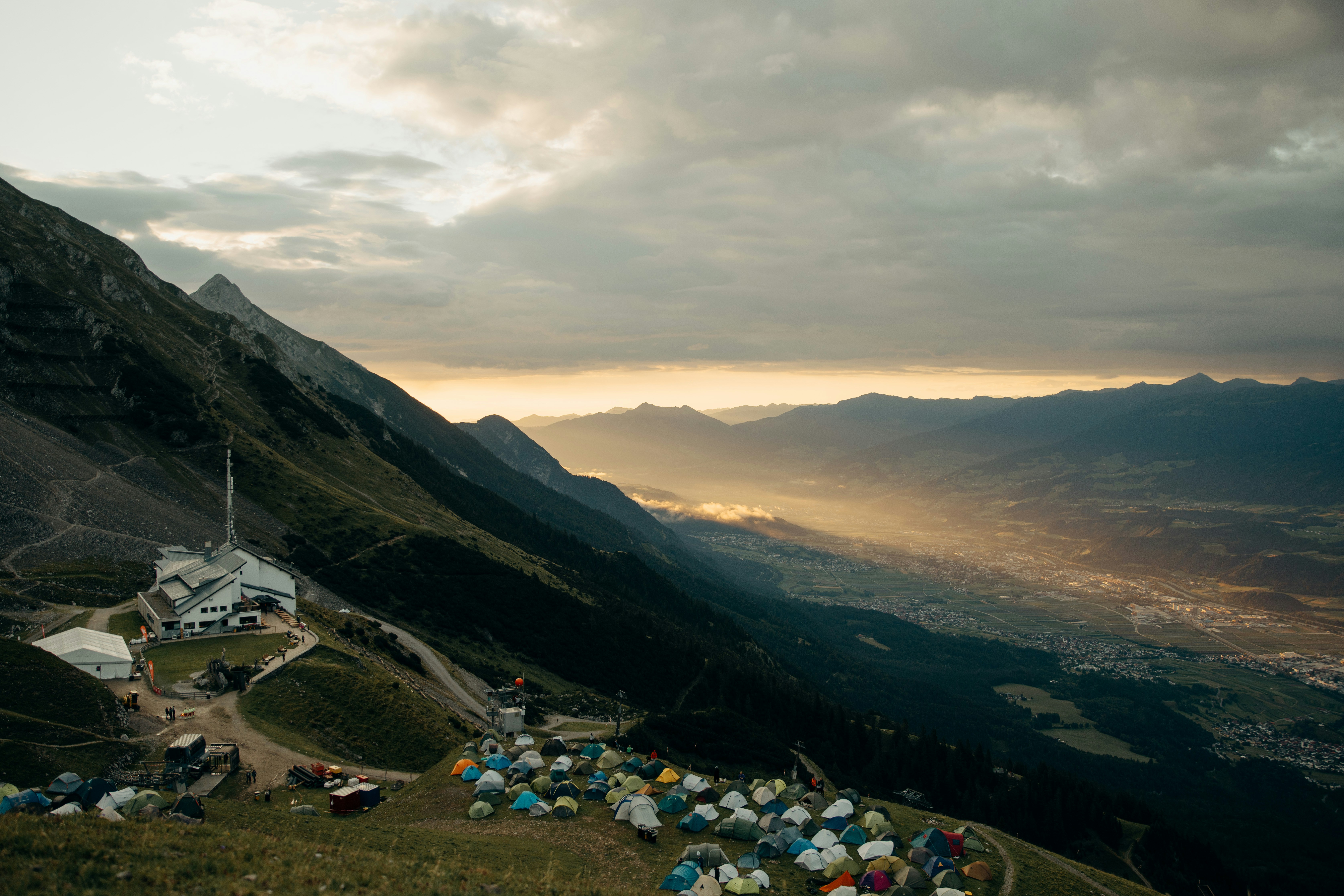Mountain campsite overlooking a sunlit valley at dusk.