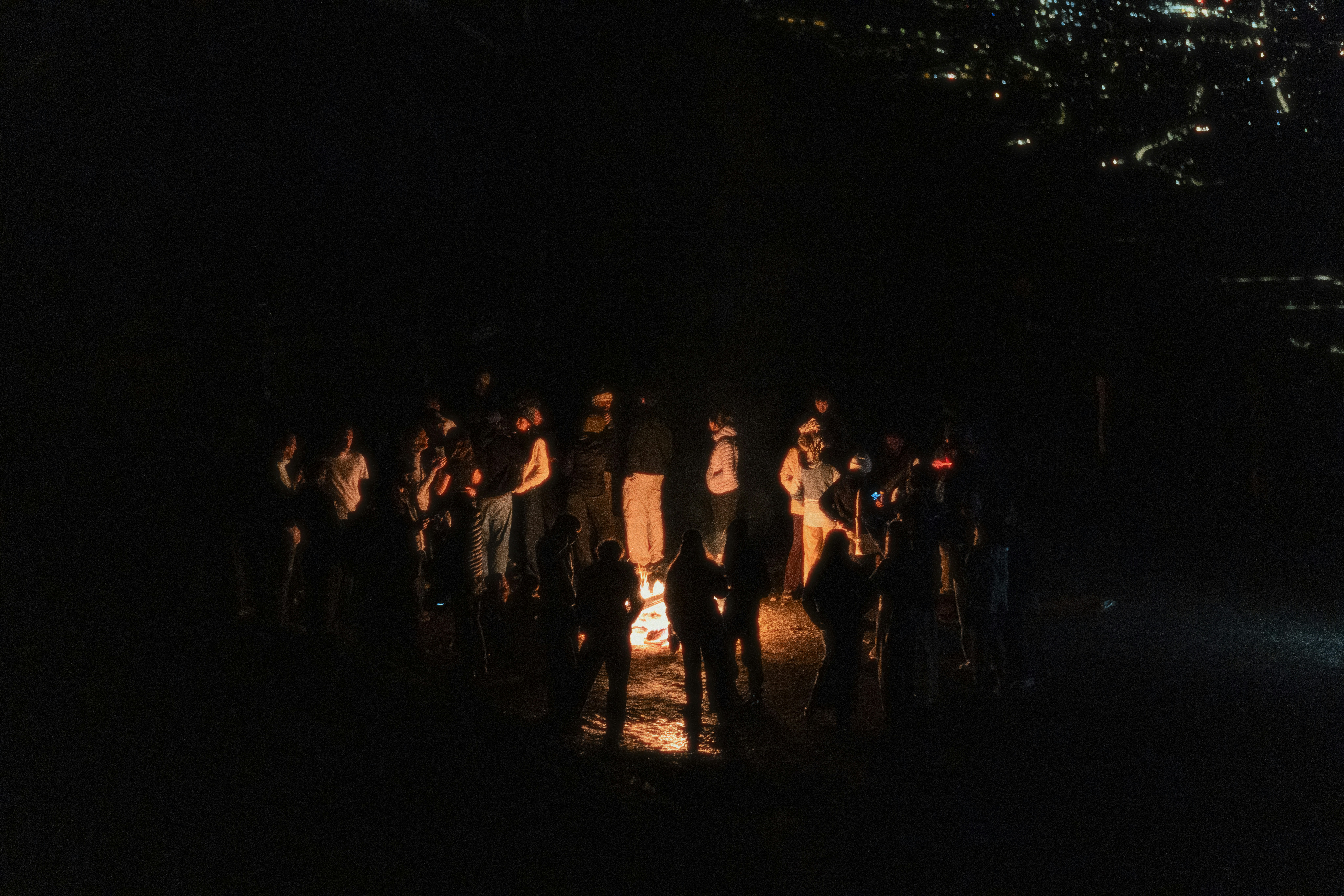 A group of people gathered around a campfire at night.
