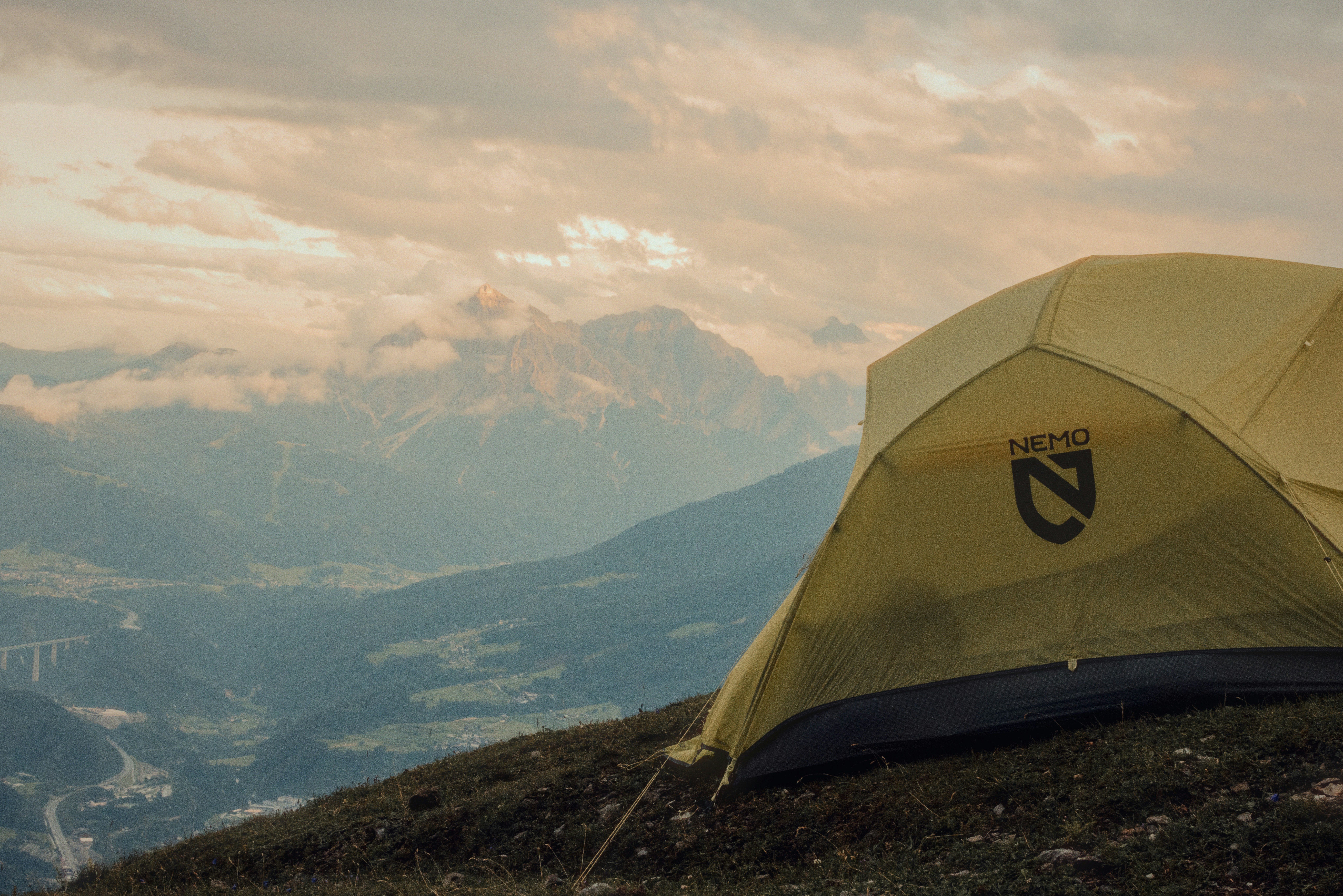 Yellow camping tent on a mountain with a cloudy sky