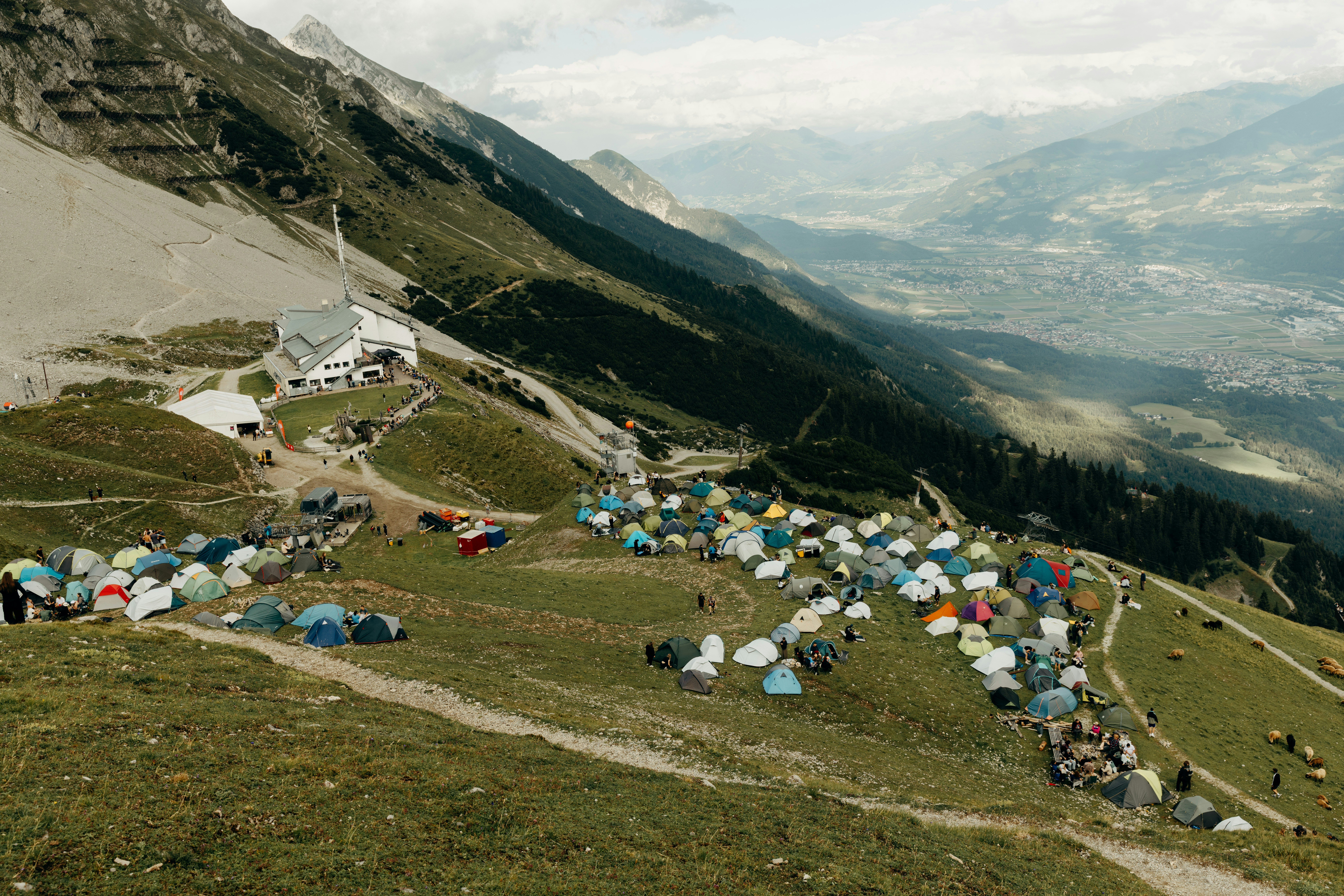 Numerous tents on a mountain slope overlooking a scenic valley.