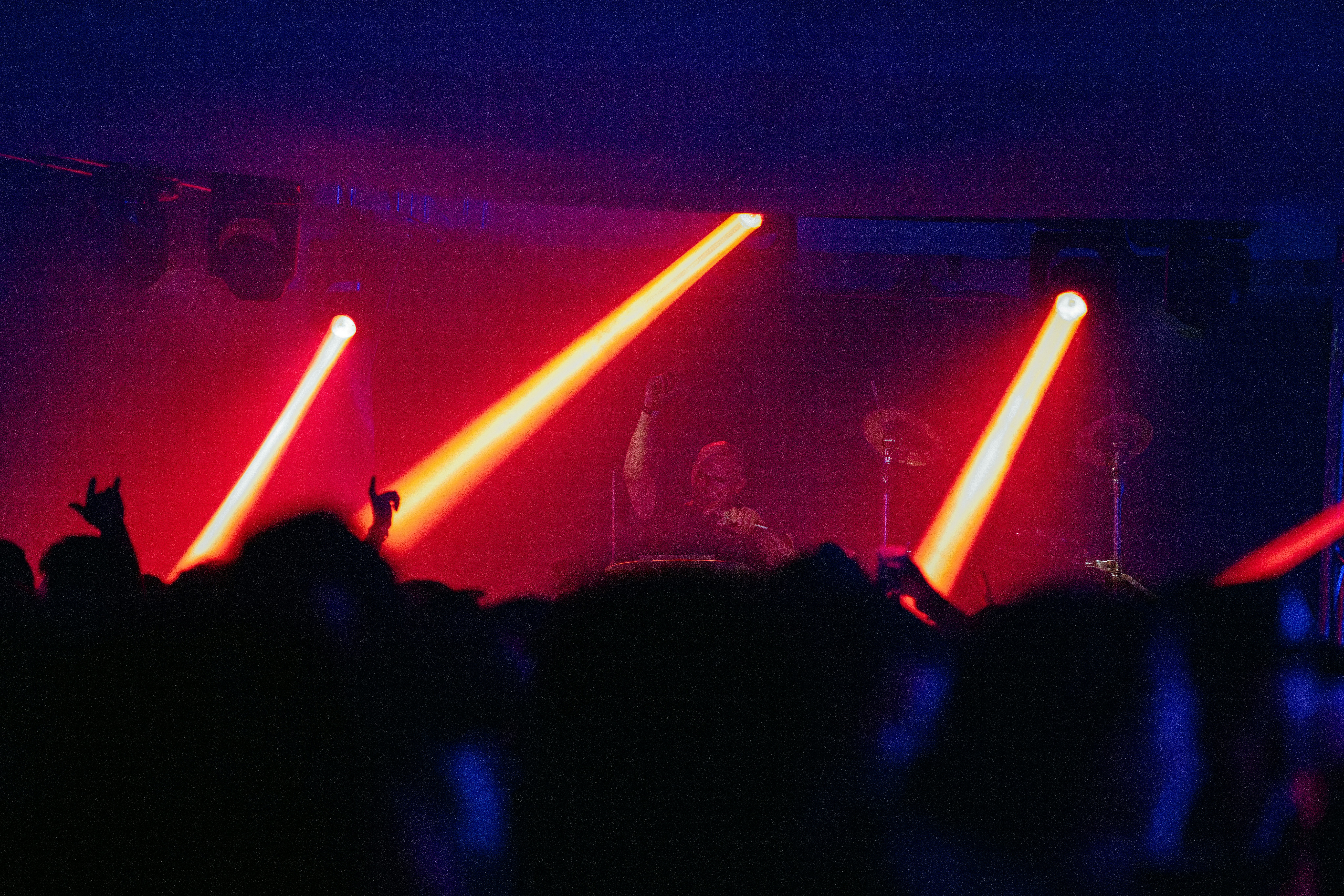 Concert crowd enjoying red stage lights and a performer.