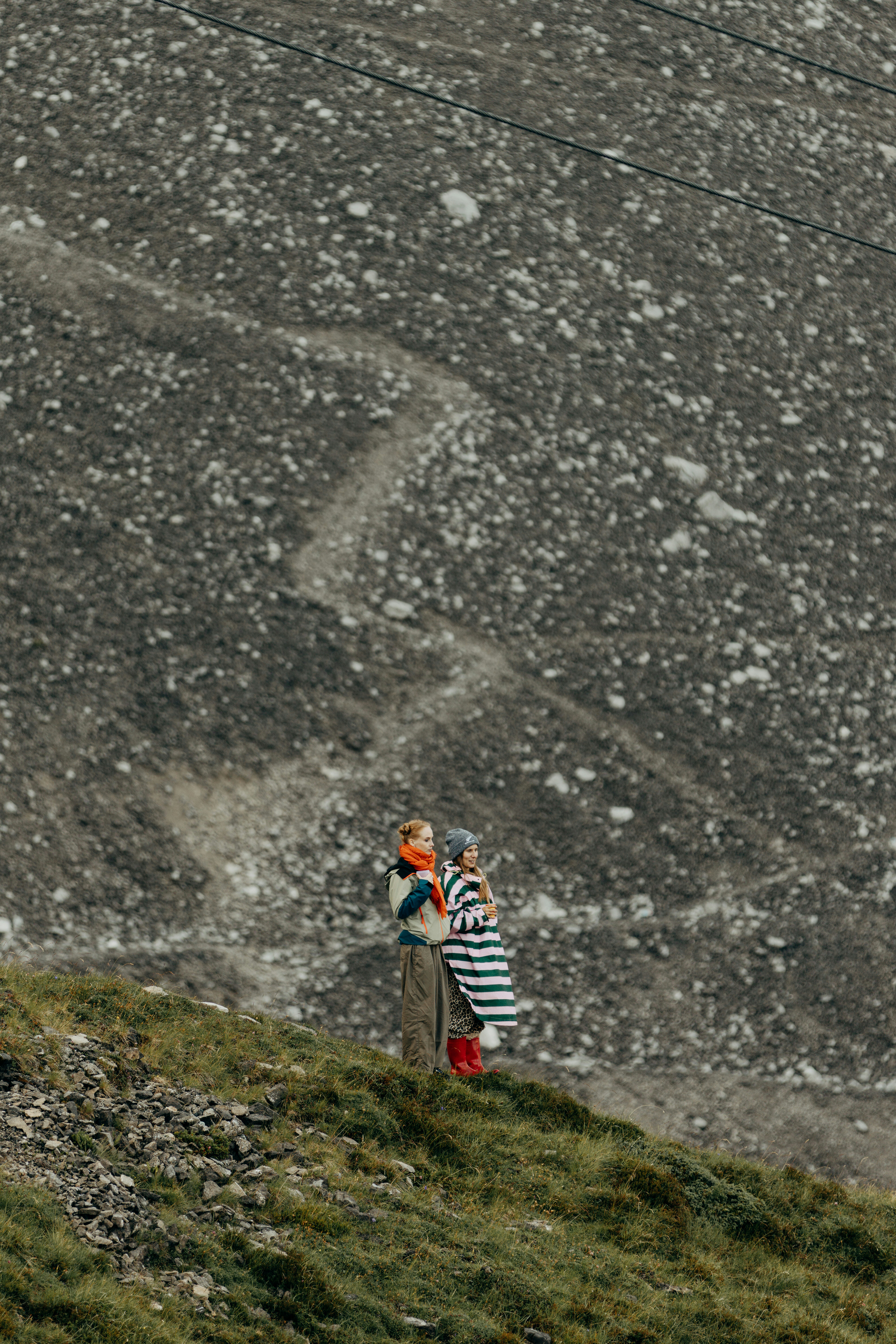 Woman holding child on a rocky mountain slope.