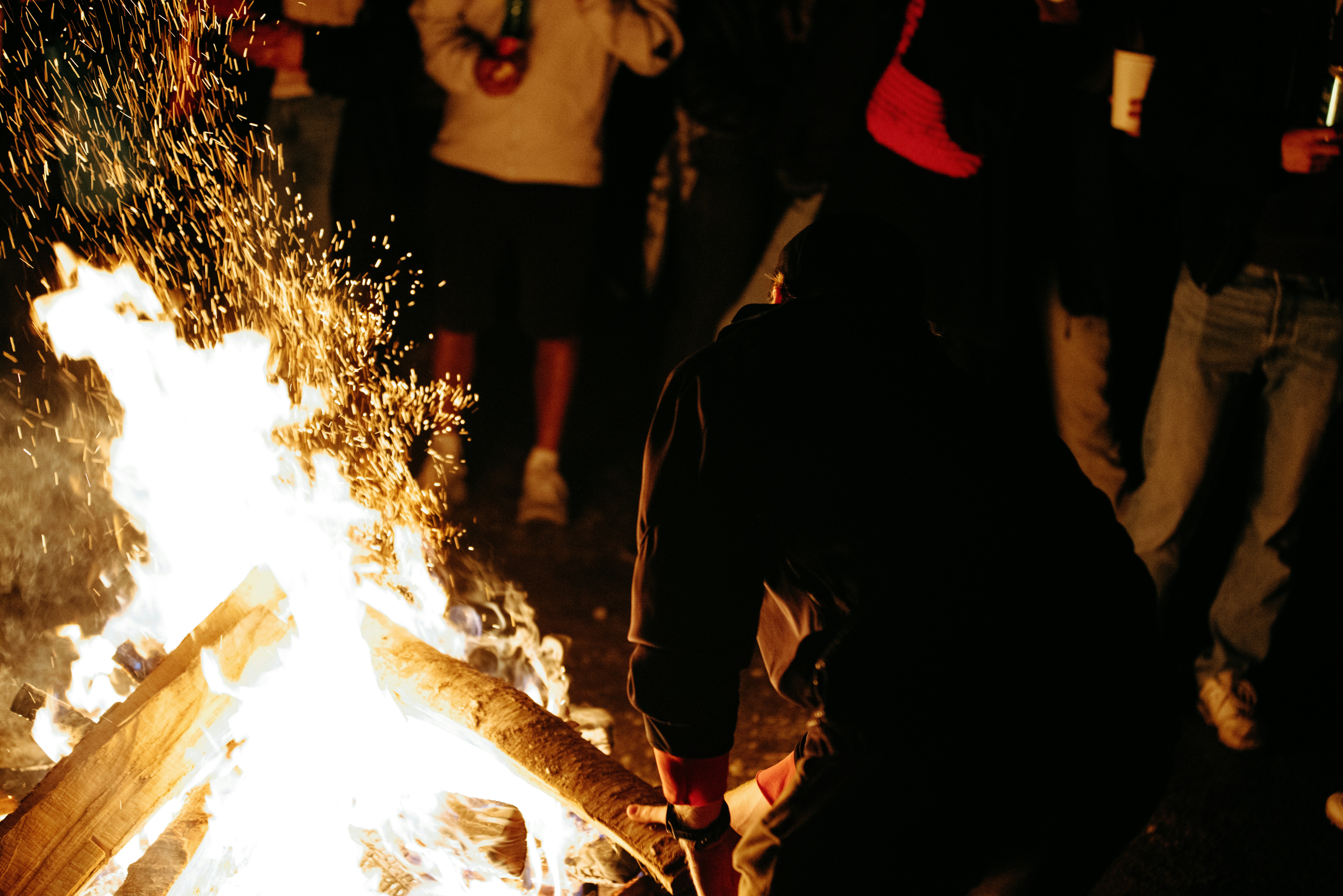 People gathered around a bright bonfire at night.