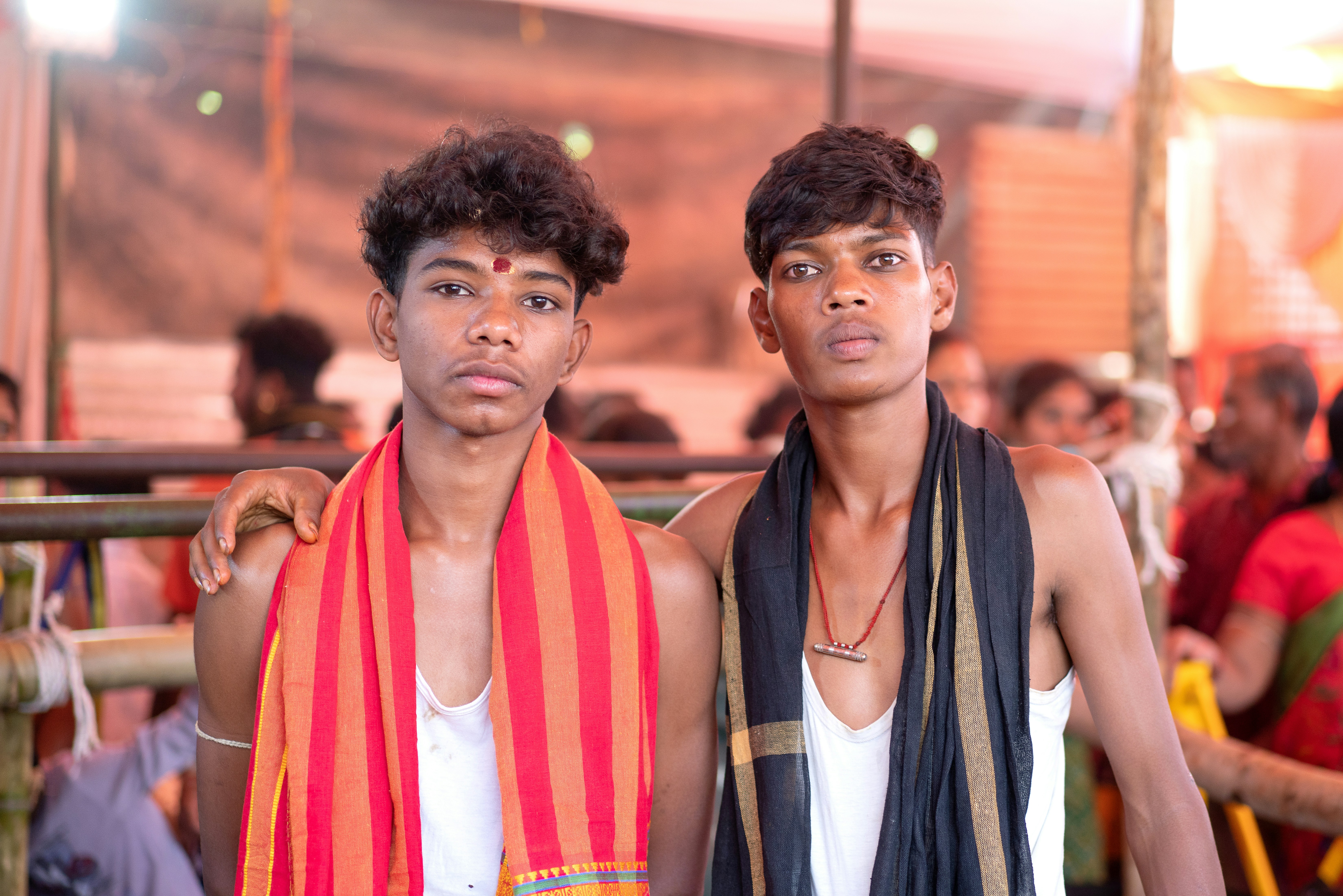 Two young men with colorful scarves stand together.