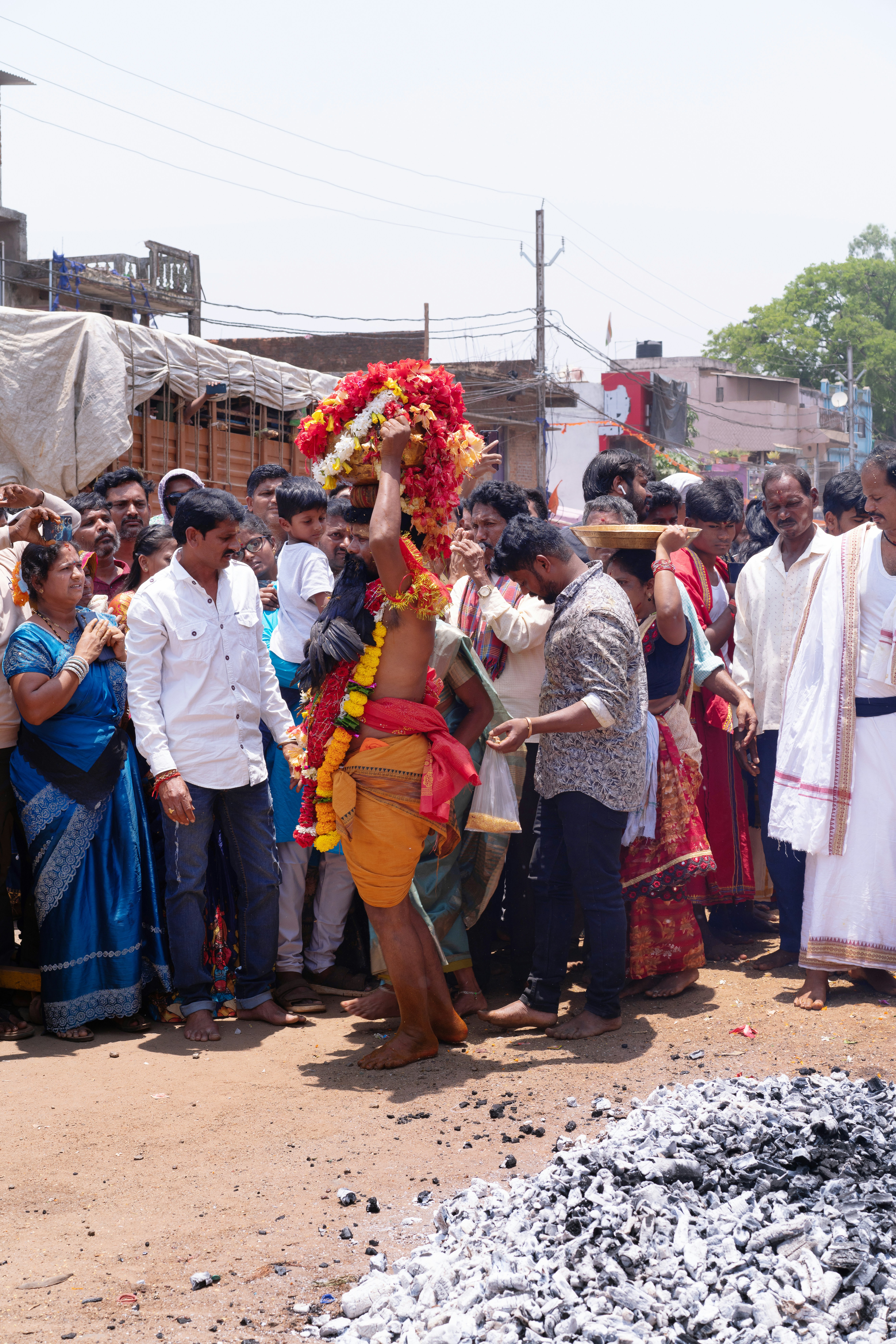 Man walks on hot coals with floral decorations on head.