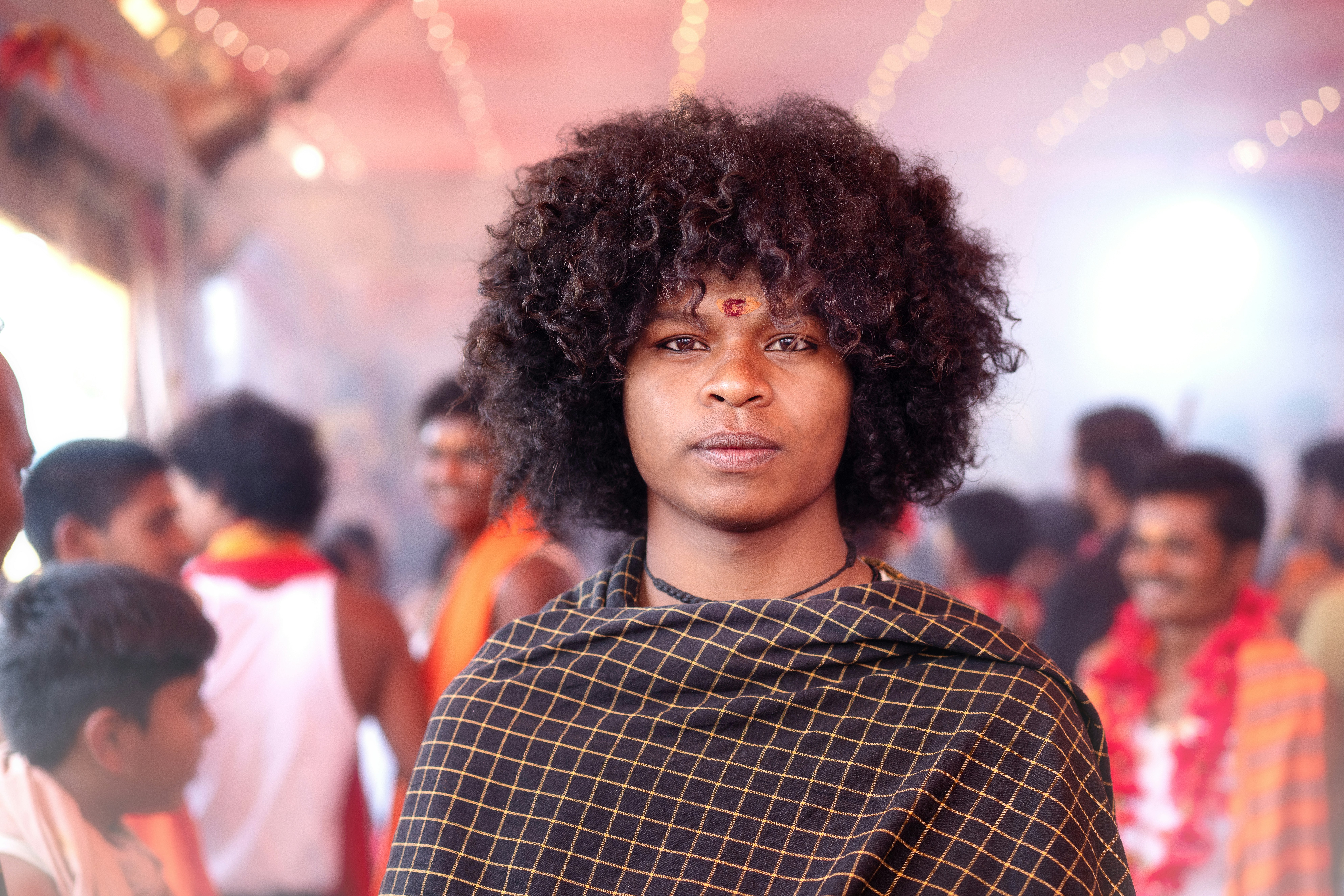 Person with curly hair and shawl in a crowded setting