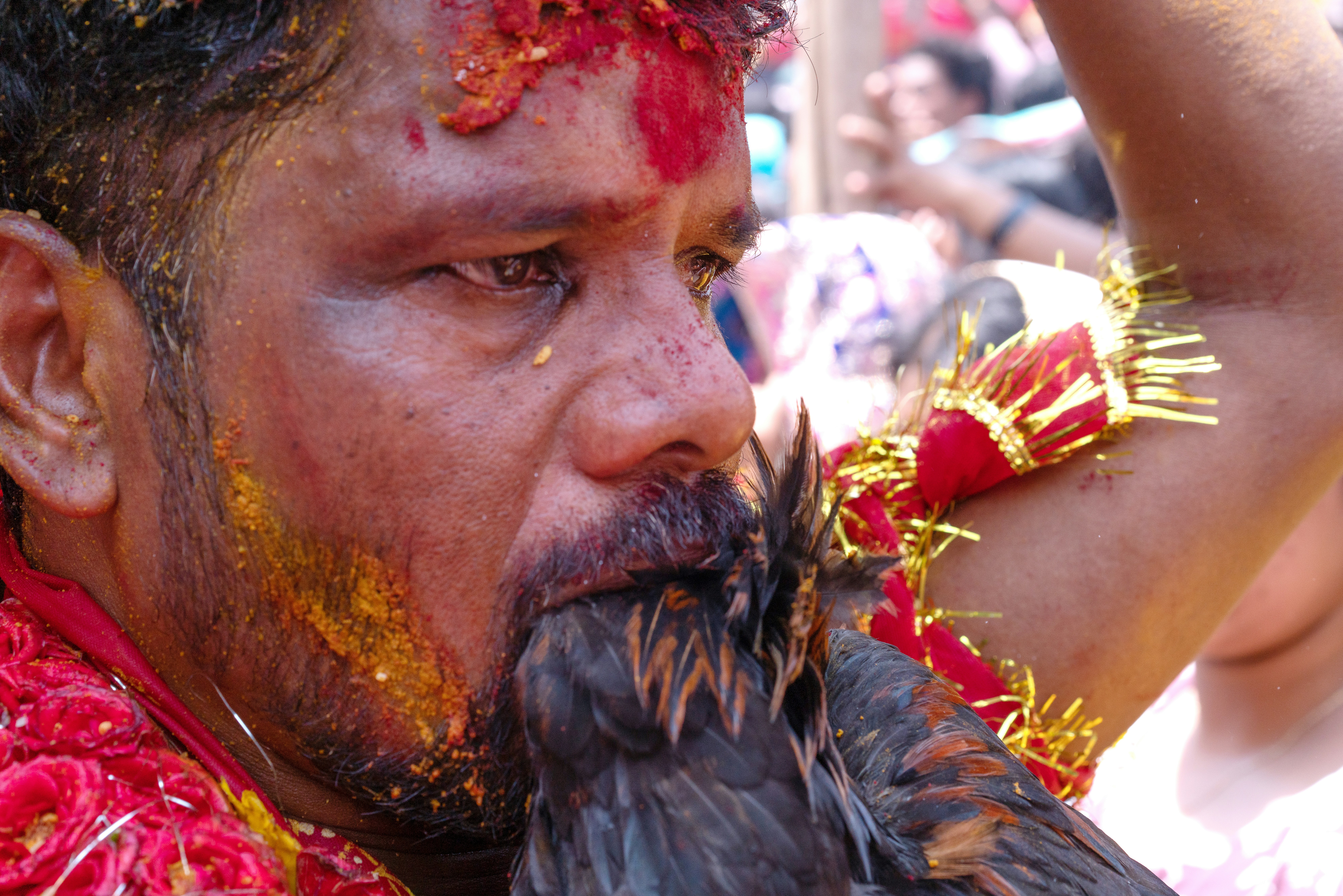 Man with ritual powder on face holds black chicken.
