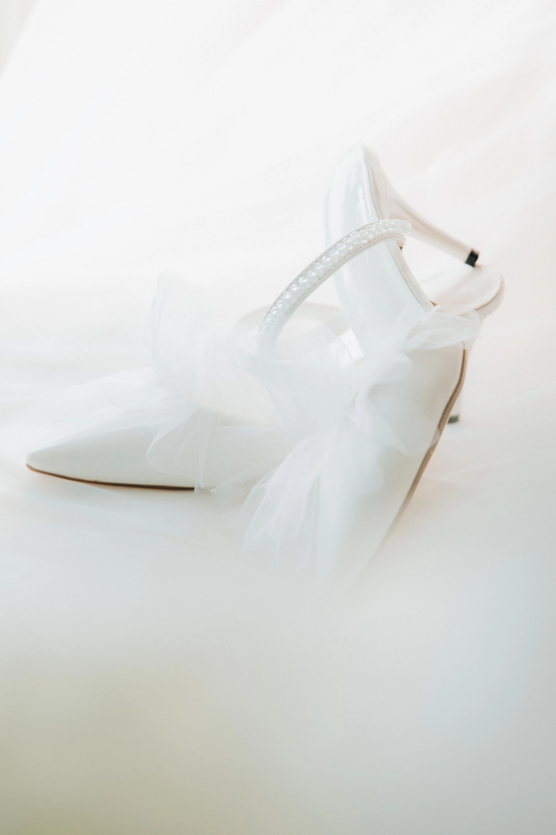 White high-heeled shoes with tulle on a light background