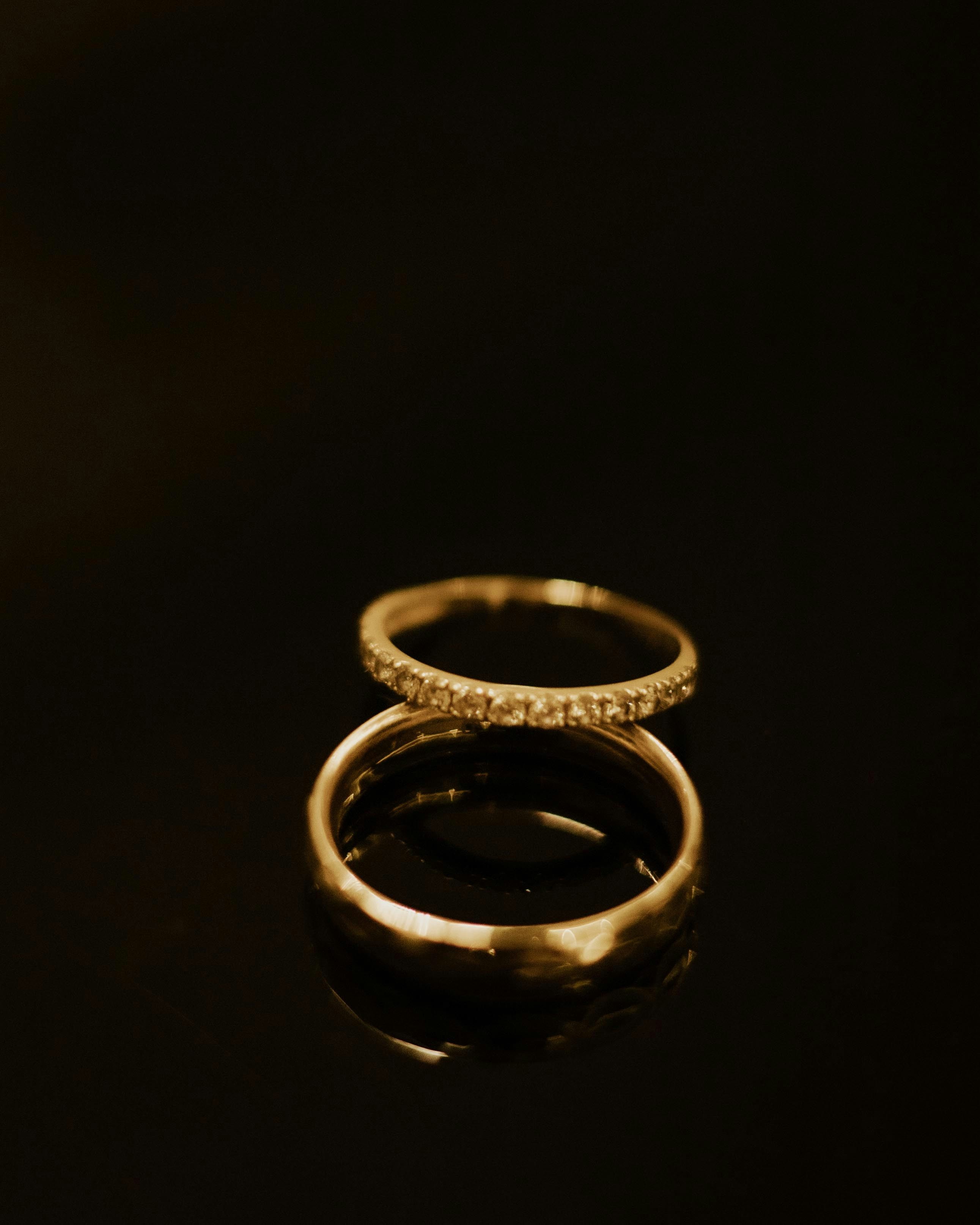 Two gold wedding rings stacked on a dark surface