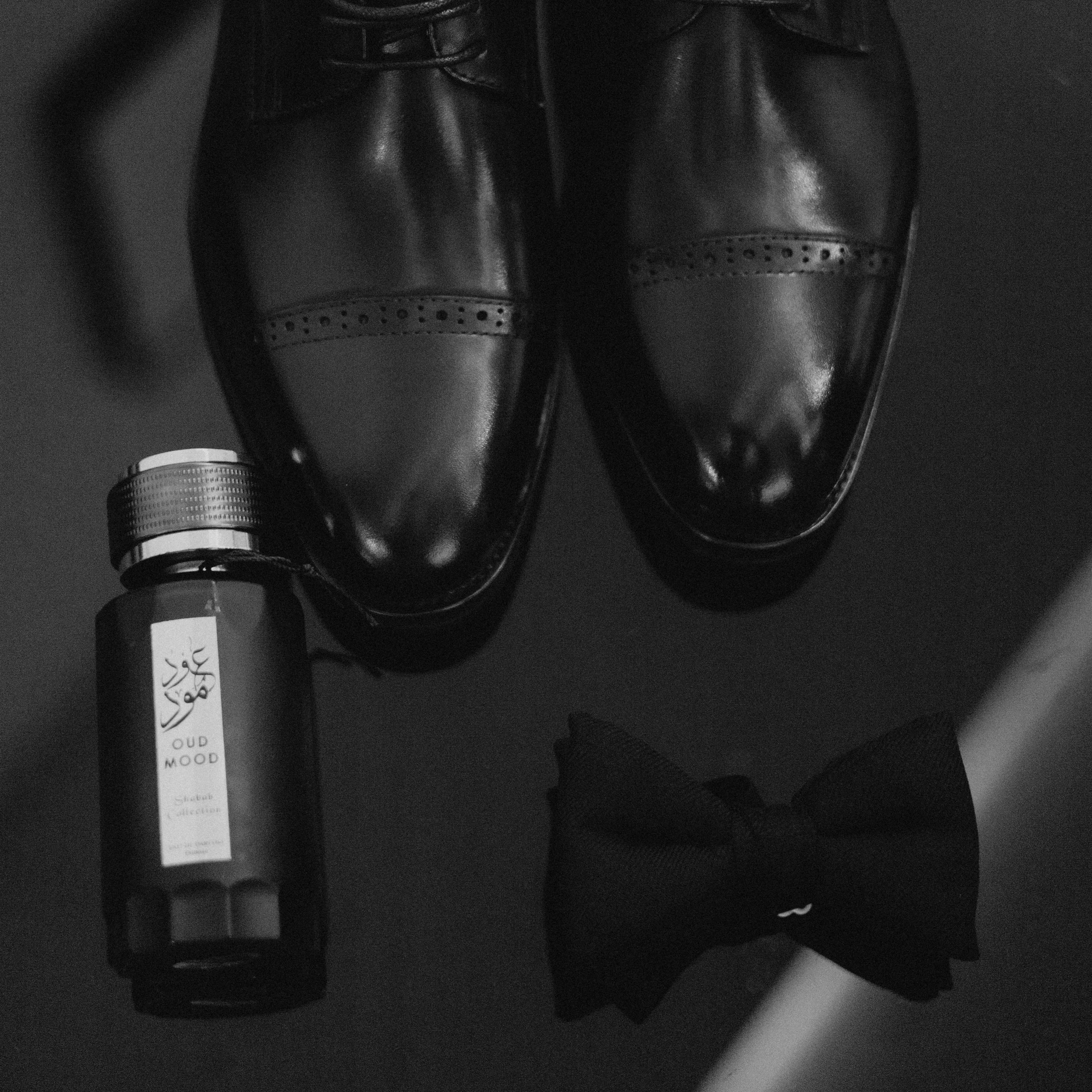 Black dress shoes, perfume bottle, and a bow tie