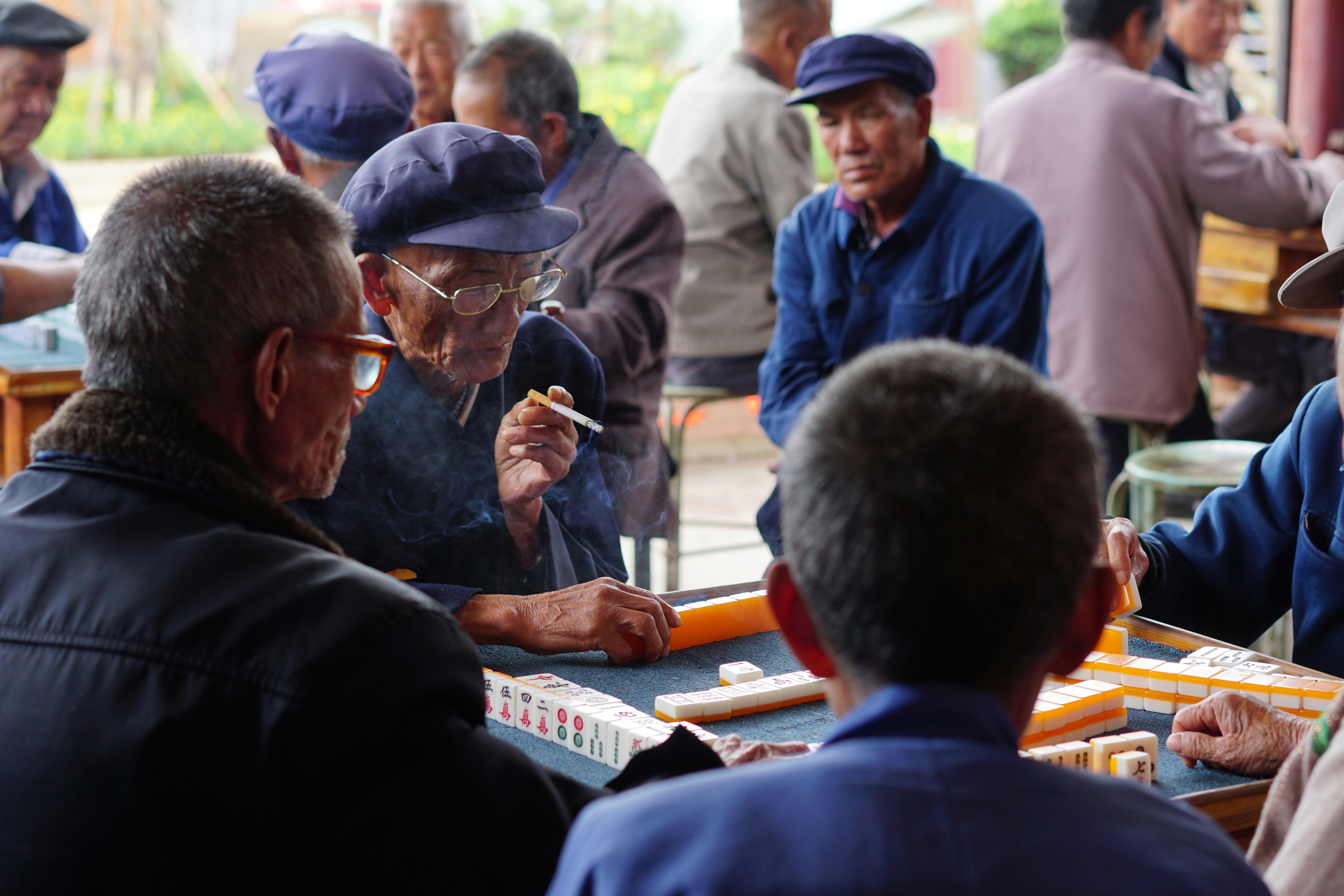 Hombres mayores jugando al mahjong y fumando en una reunión social