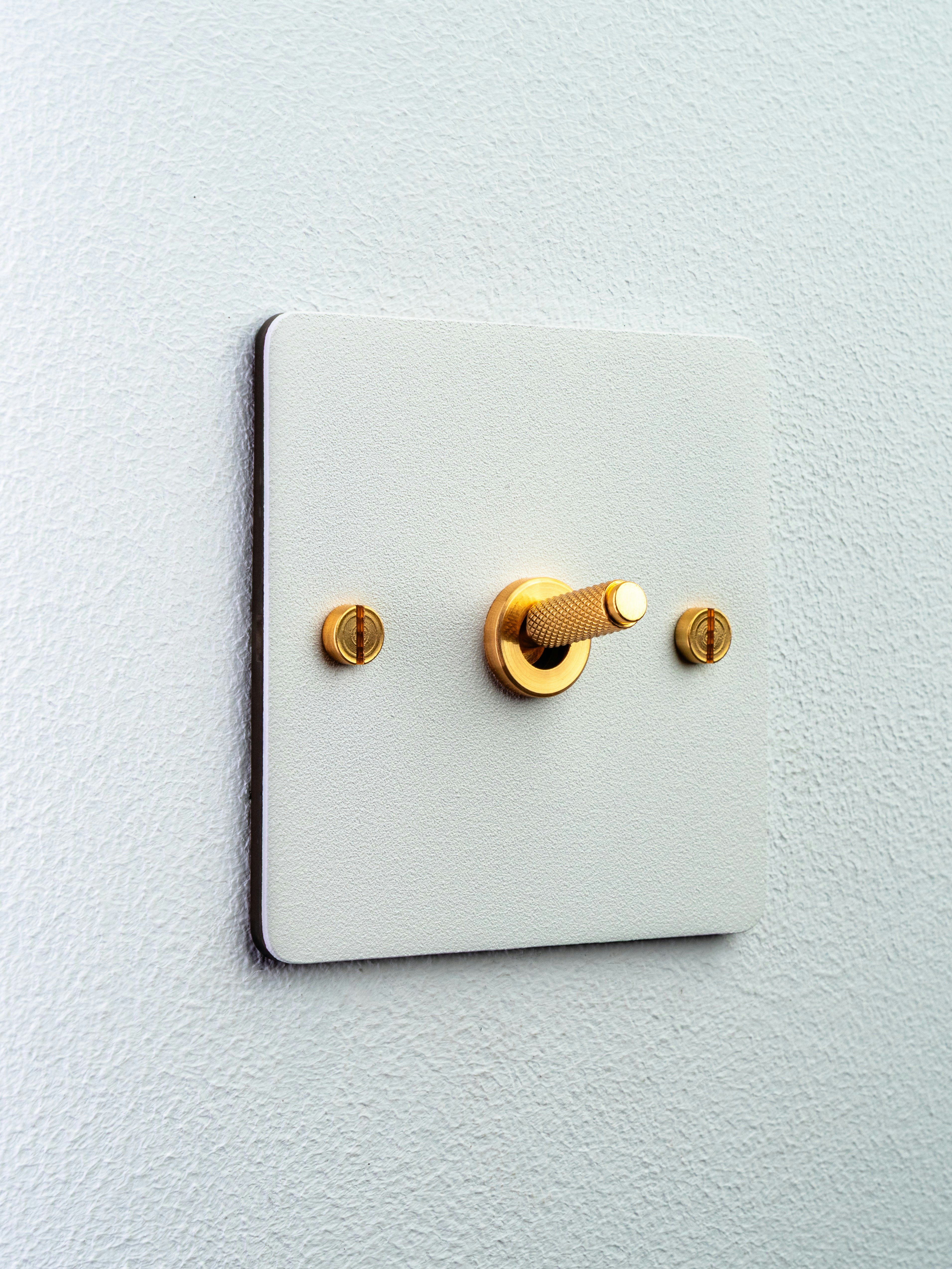 Brass toggle light switch against a clean white wall