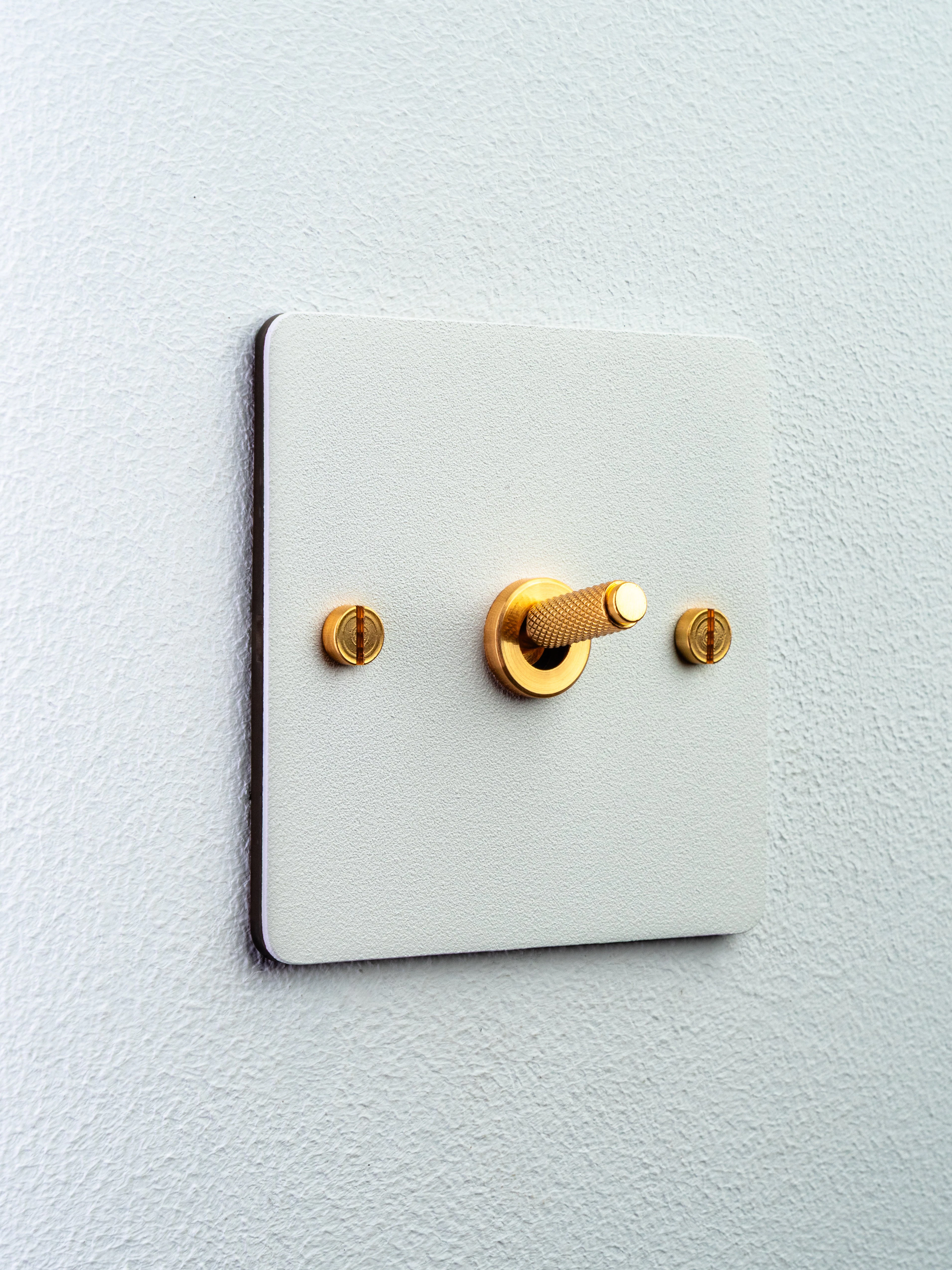 Brass toggle light switch on a white wall