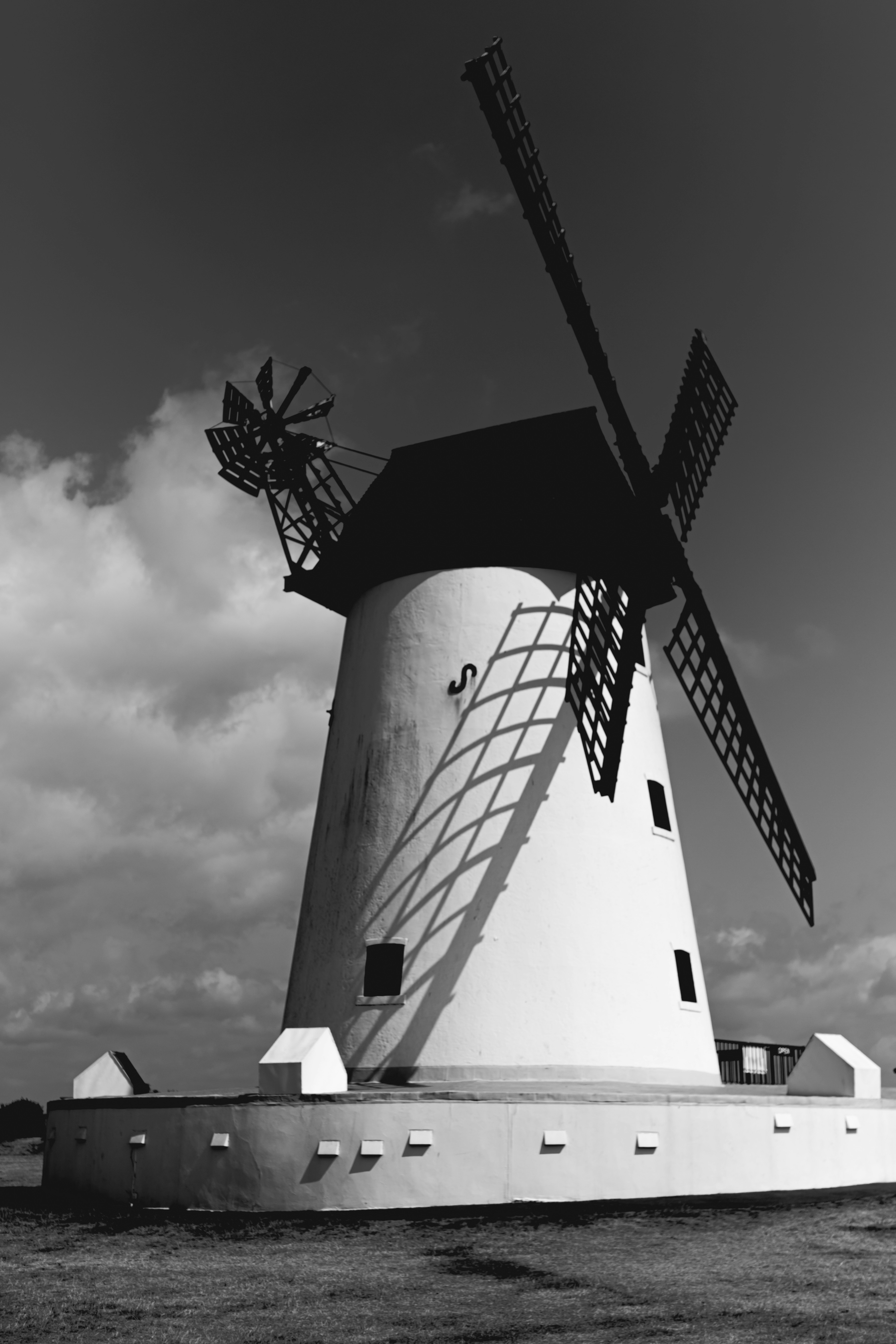 White windmill with prominent shadows against a dramatic cloudy sky