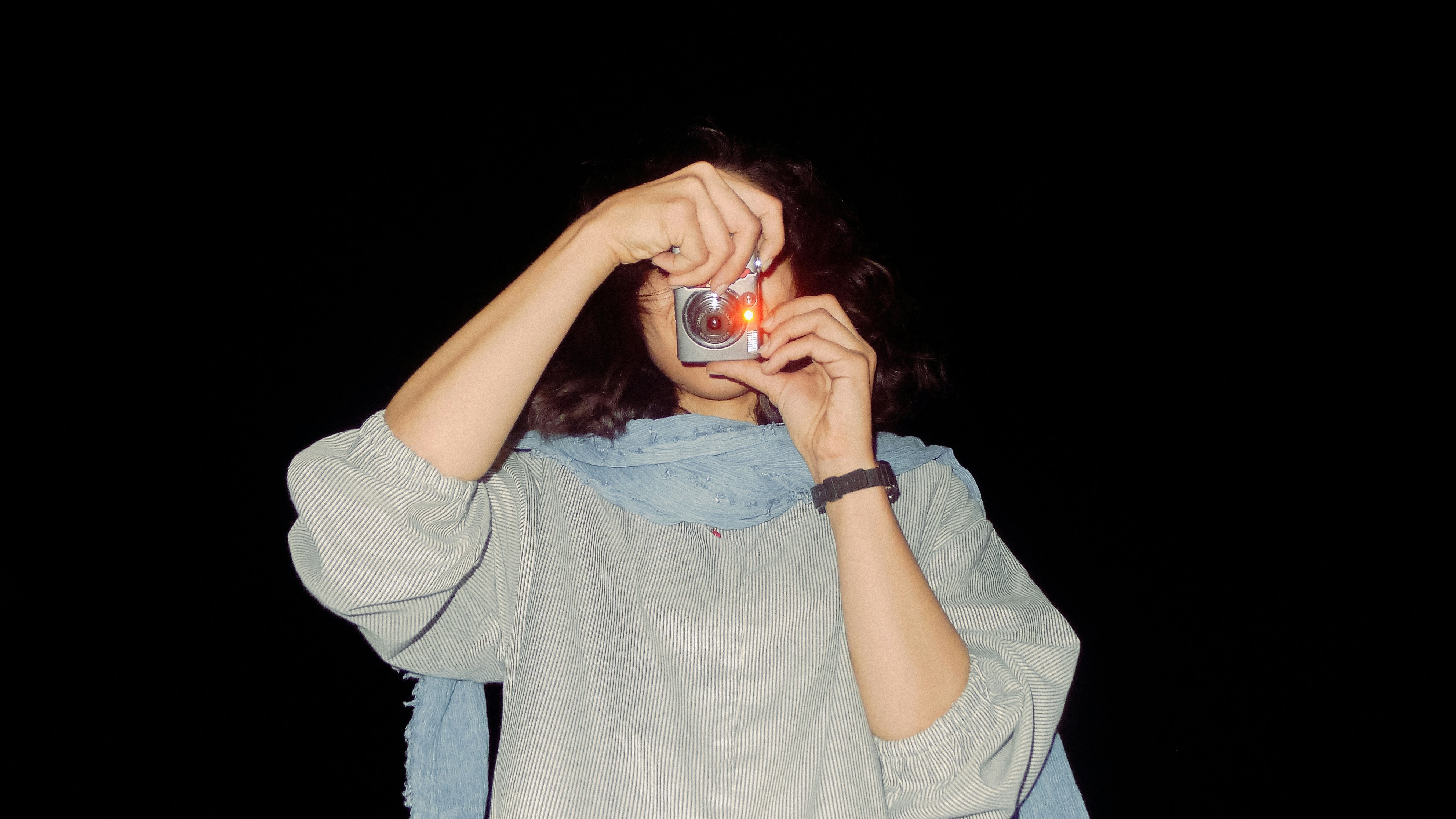A person holds a small camera up to their eye