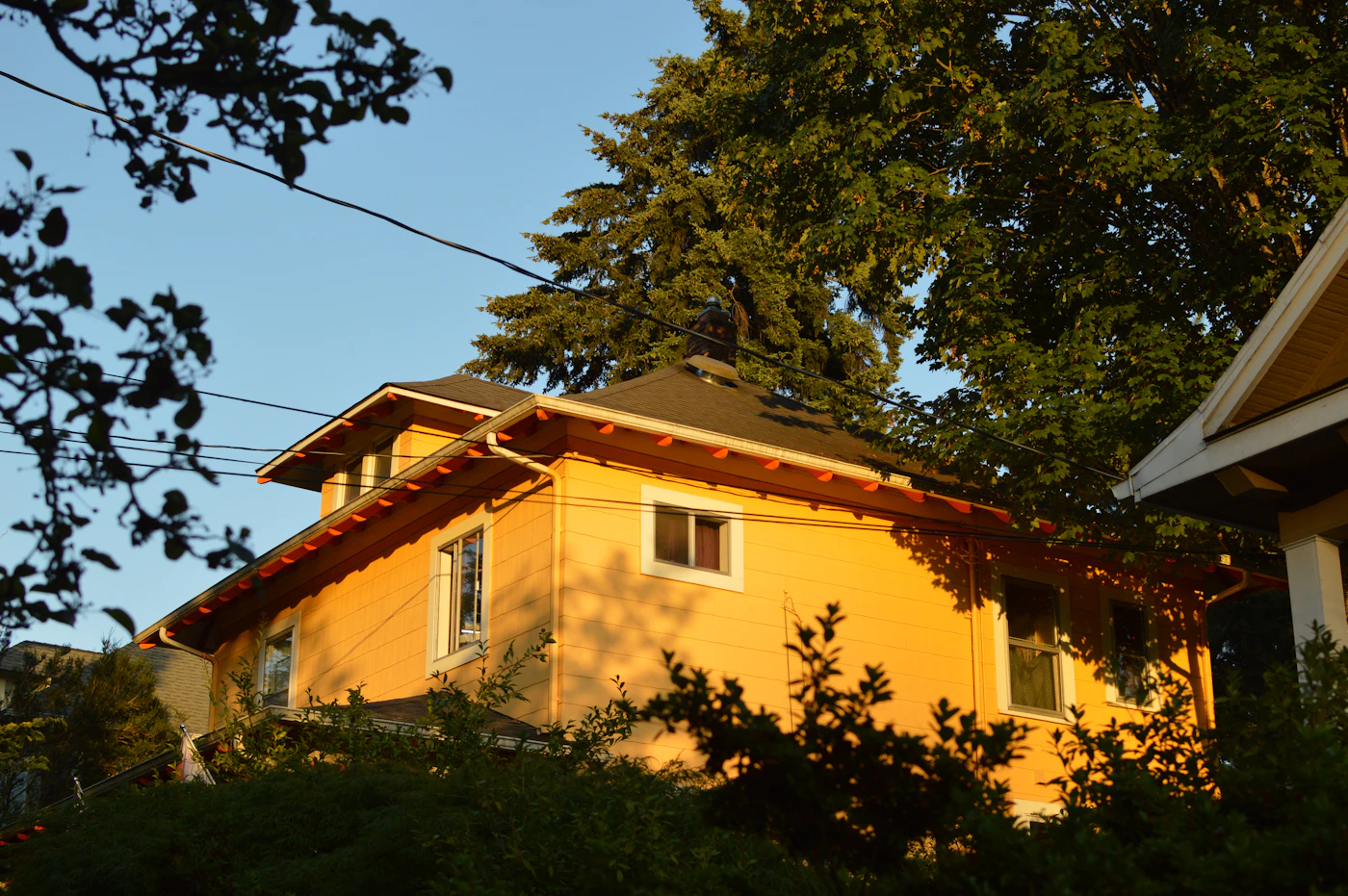 Yellow two-story house with a tiled roof in afternoon sun