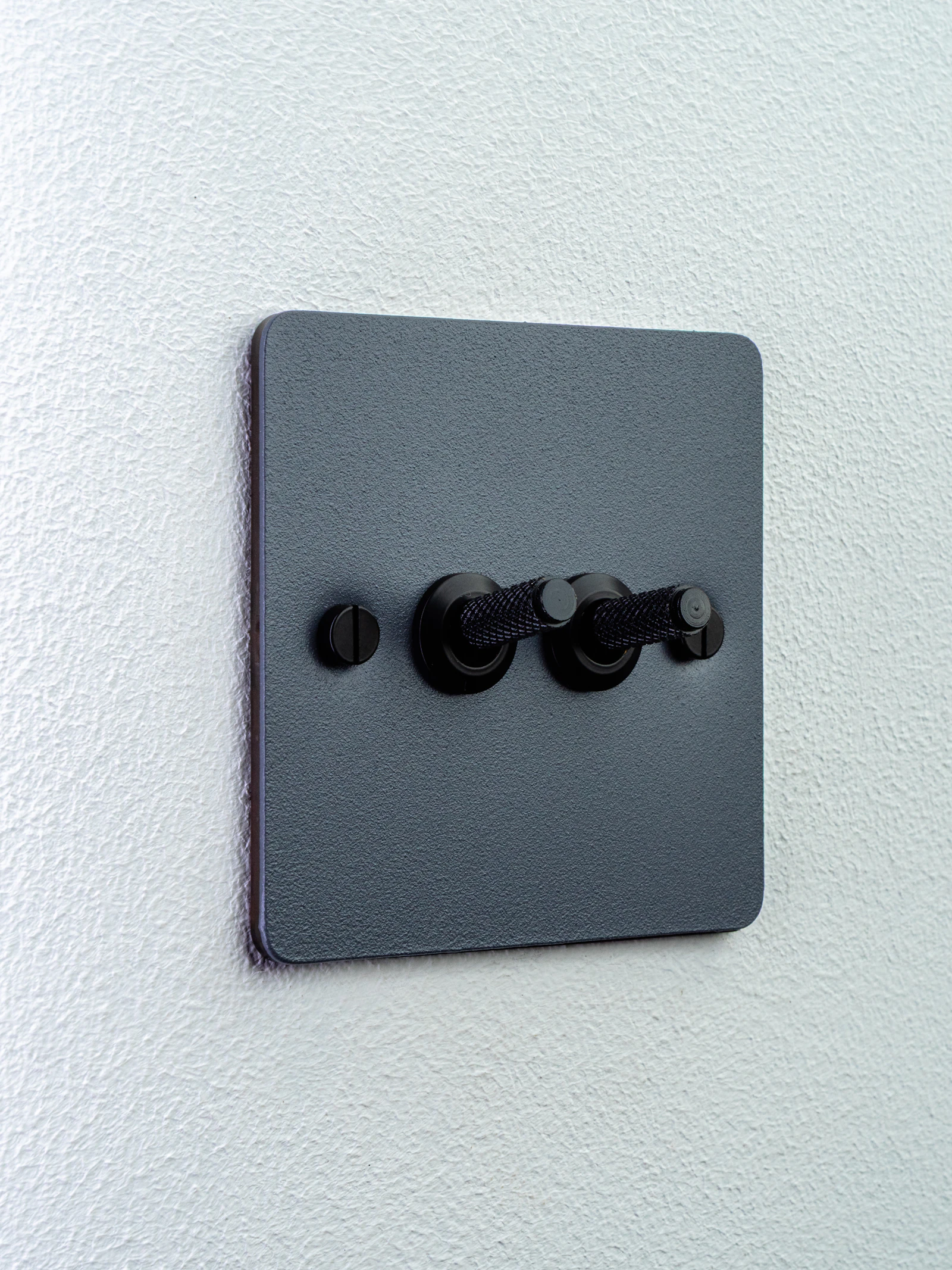 Two-gang black toggle light switch on a white wall