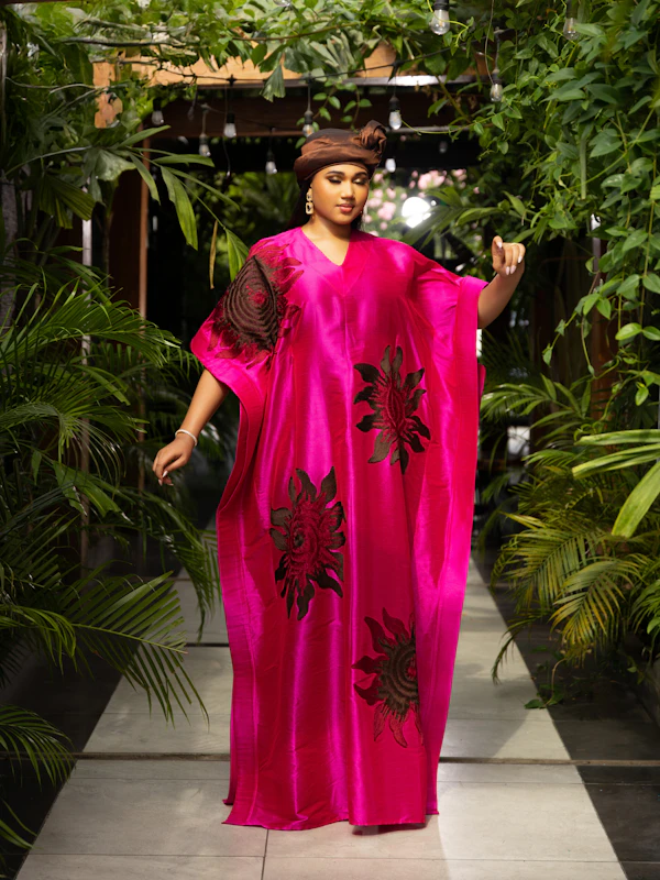 Woman in a fuchsia kaftan among green foliage