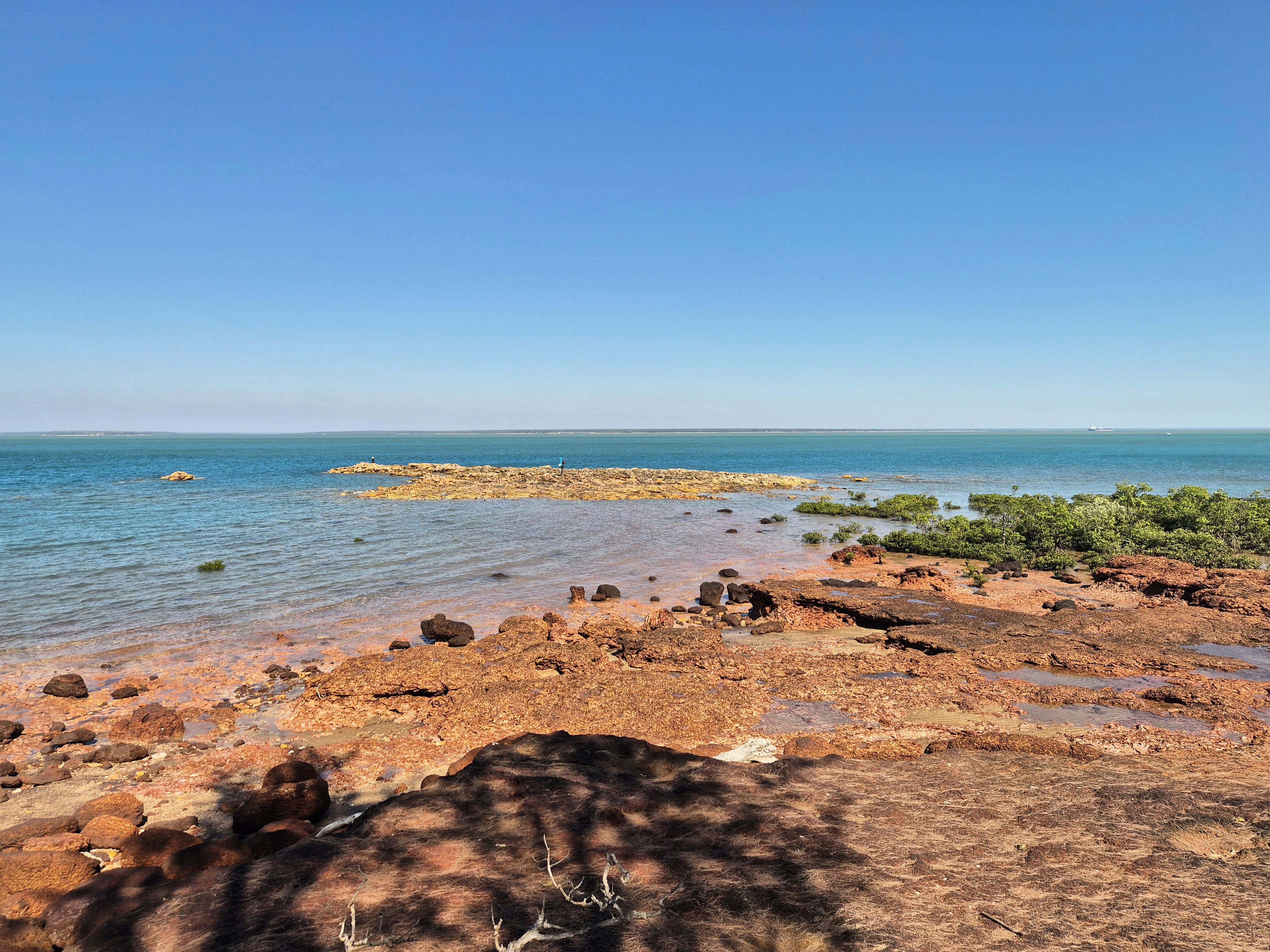 Red rocky shore by a calm blue ocean.