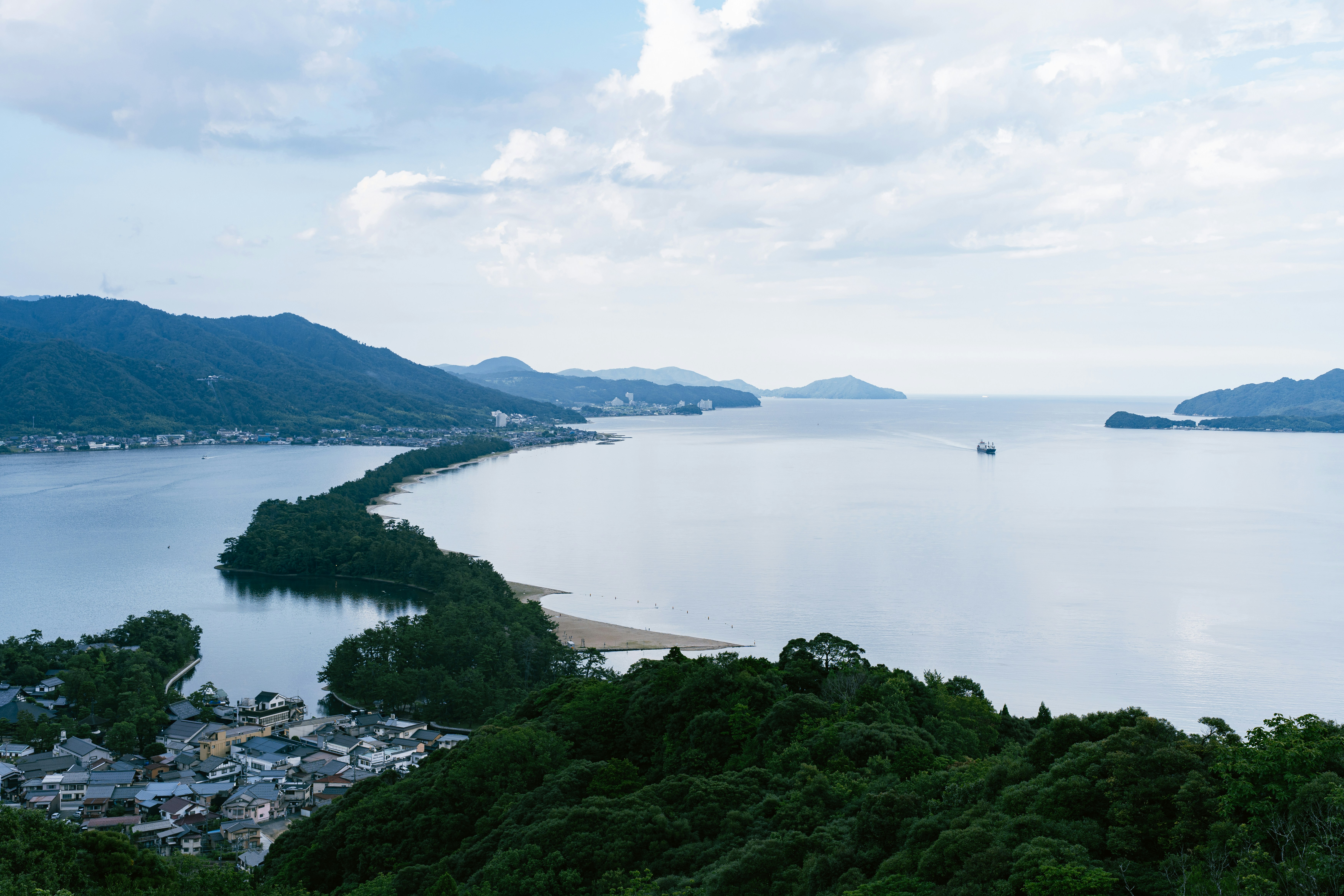 Long sandbar stretches across tranquil bay with distant mountains