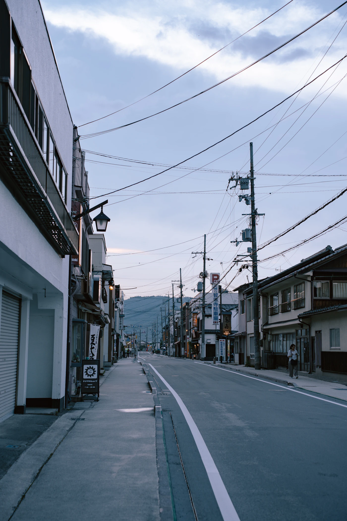 山の見える地方の町の通りと、並んで立つ電柱
