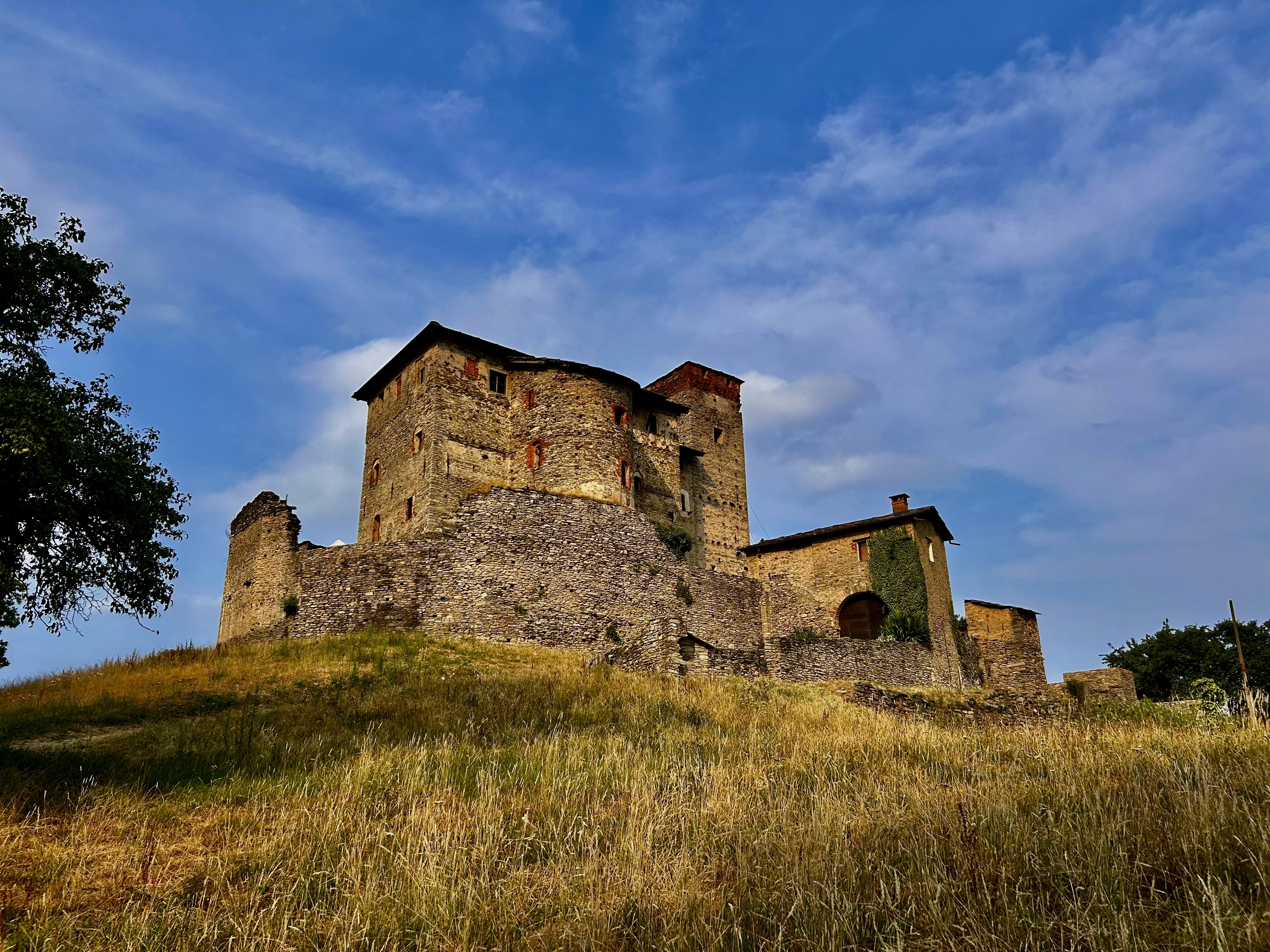 An ancient stone castle stands on a golden grassy hill