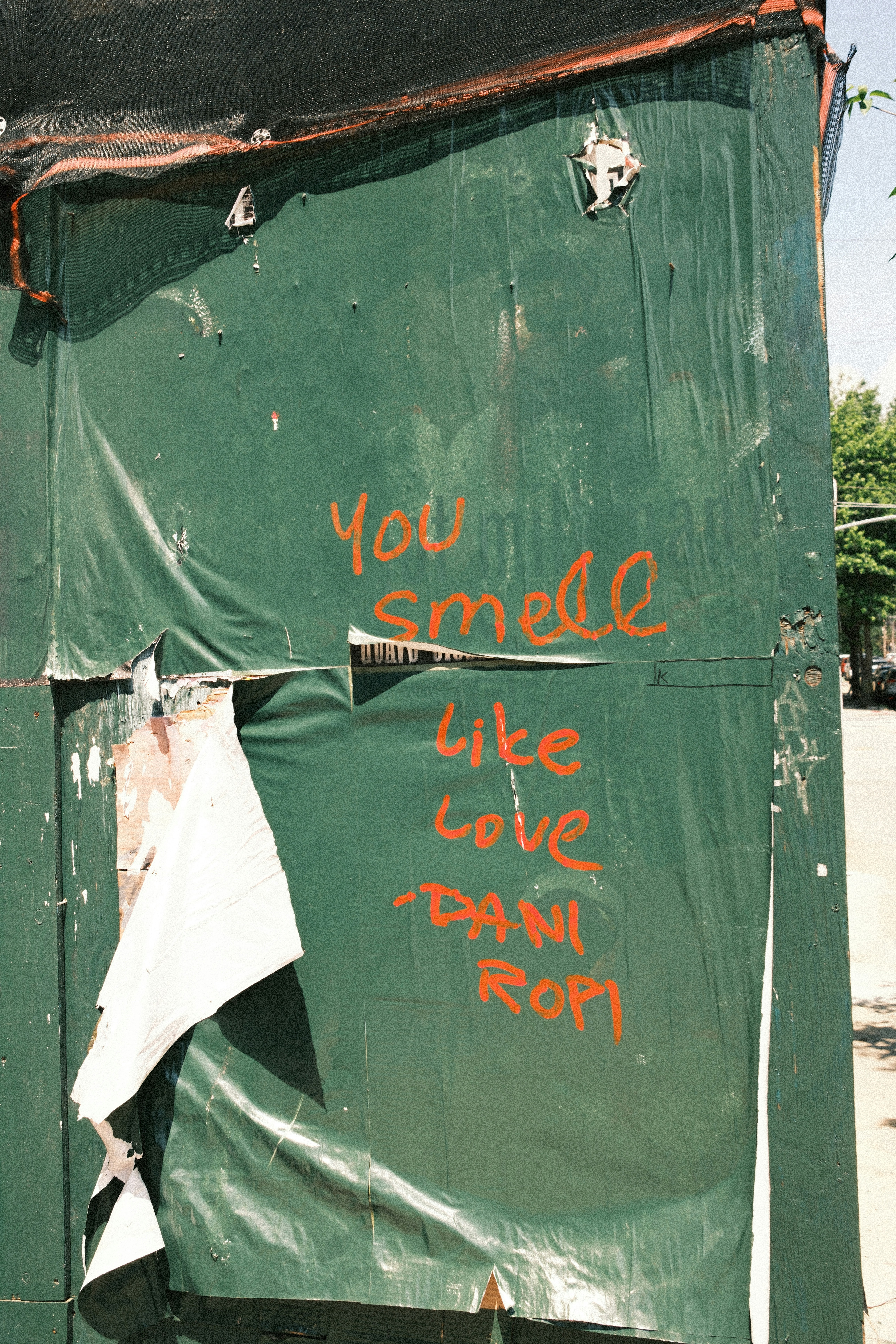 Green tarp with red graffiti reading "you smell like love"