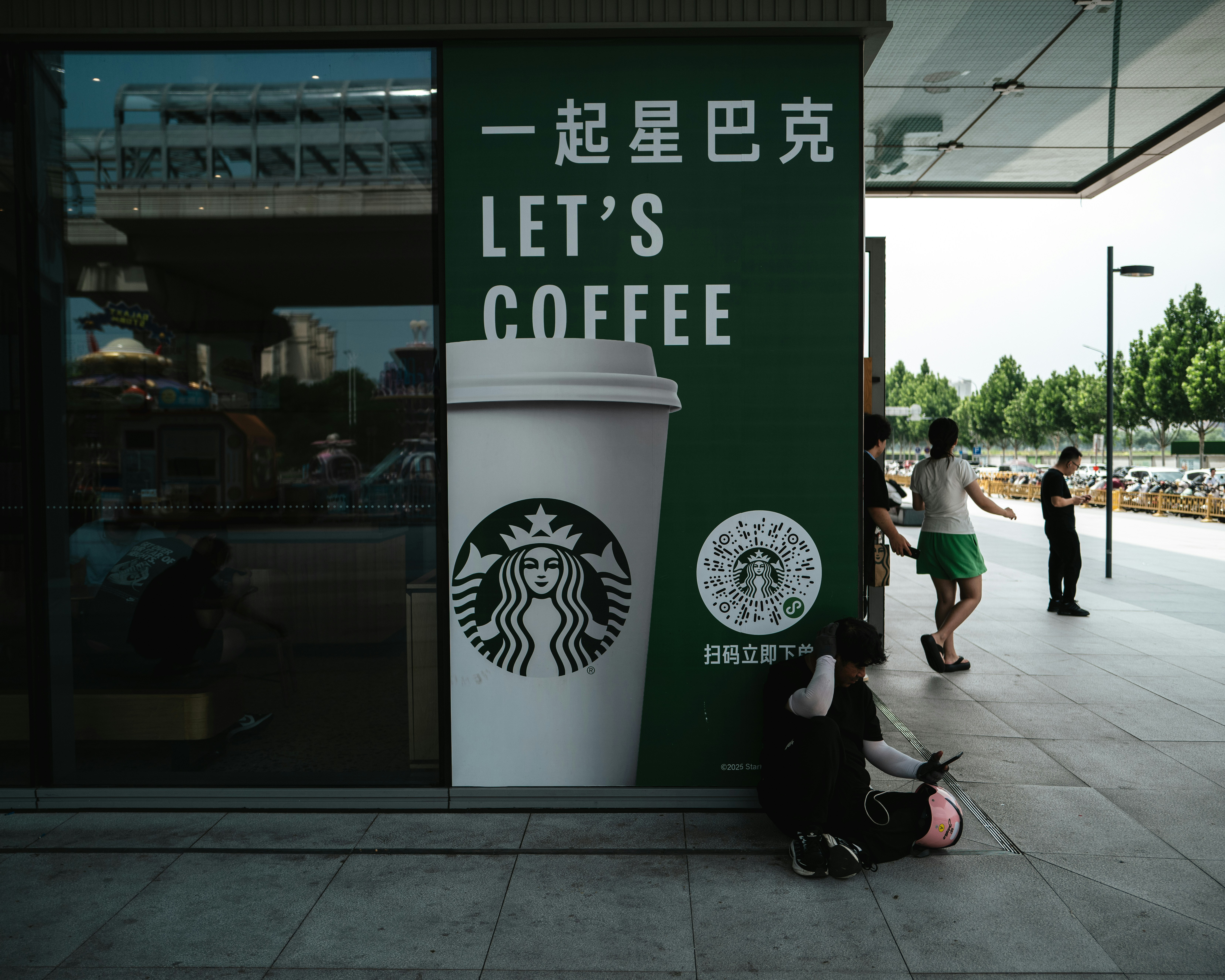 Starbucks storefront with "let's coffee" sign and people outside