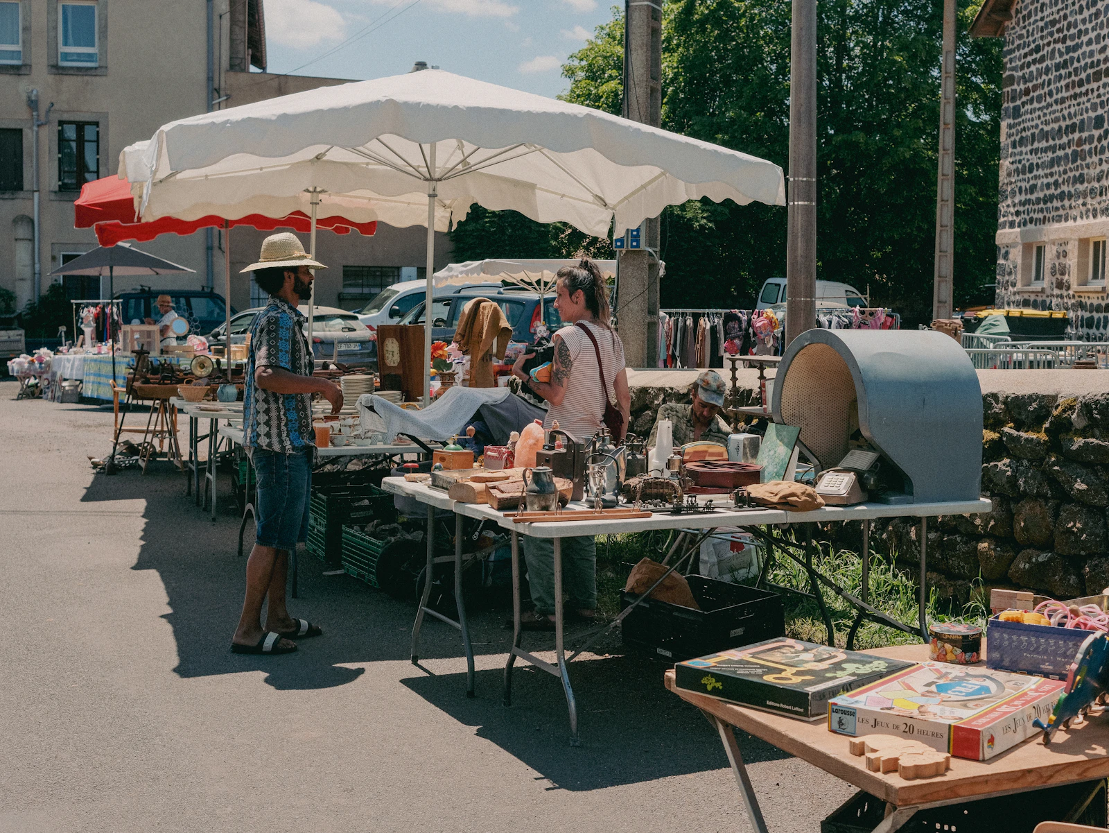 People browsing a small outdoor market stall in bright daylight