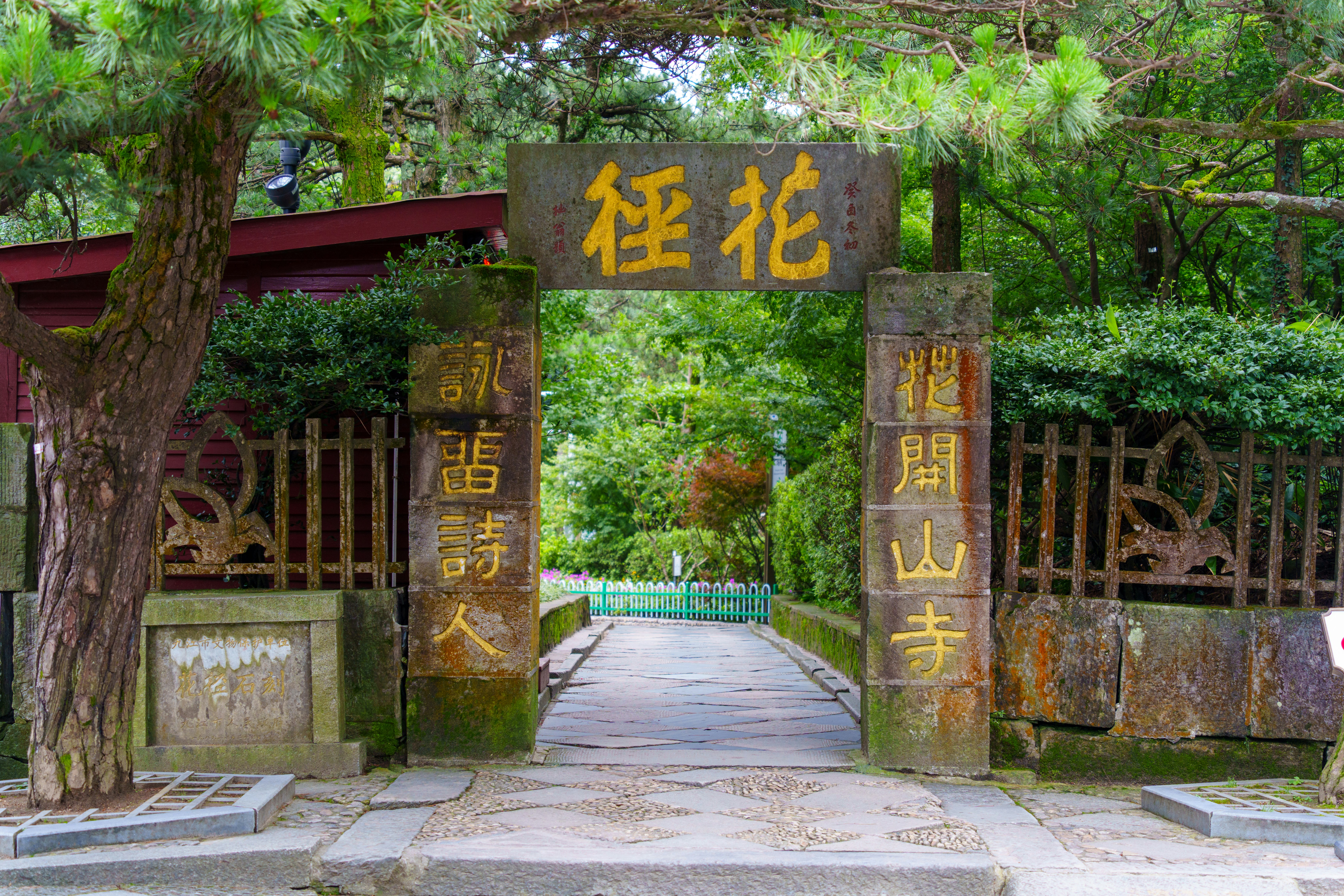 Ancient stone gateway with japanese calligraphy amidst lush green foliage
