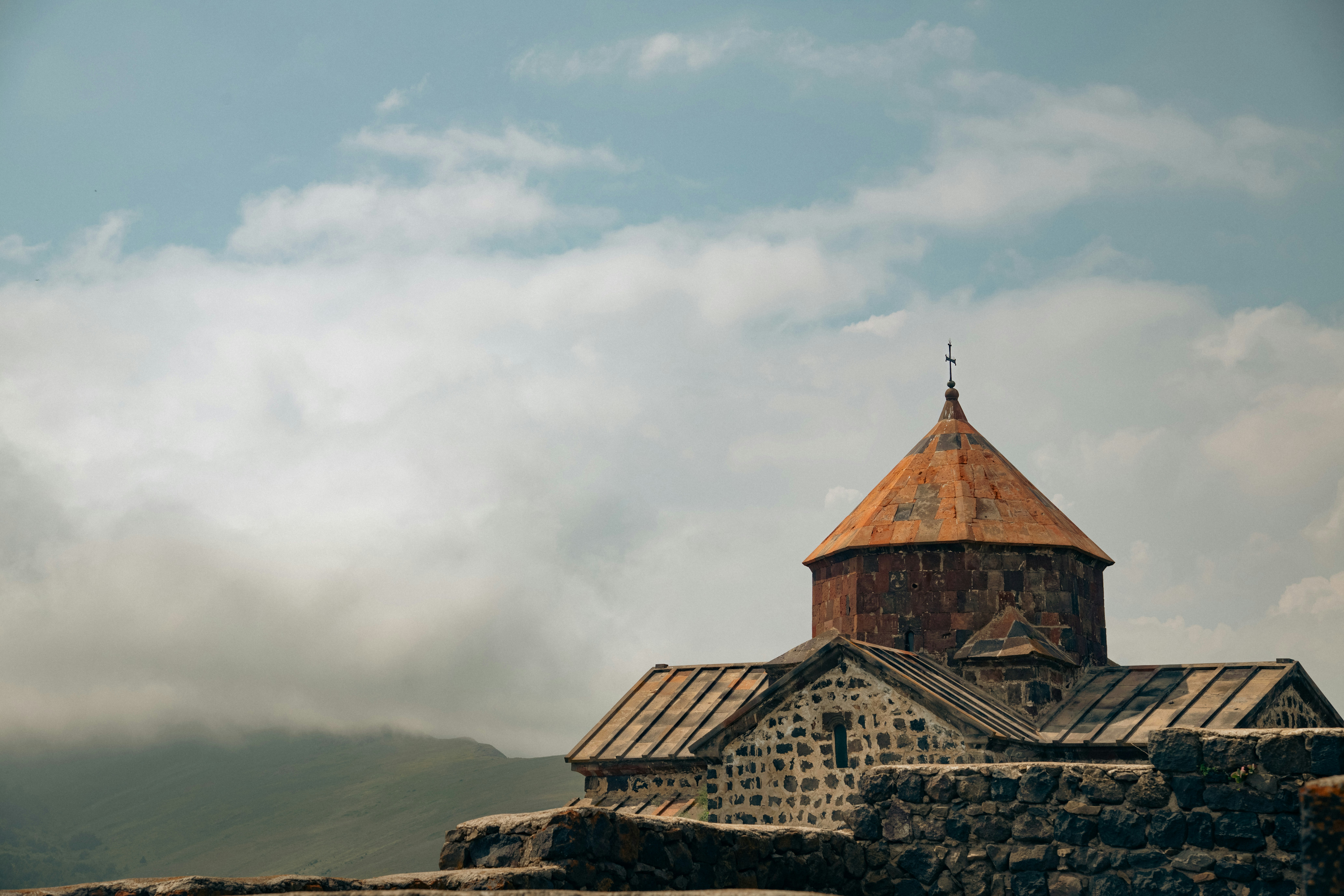 Antiga igreja de pedra com telhado laranja sob céu nublado.