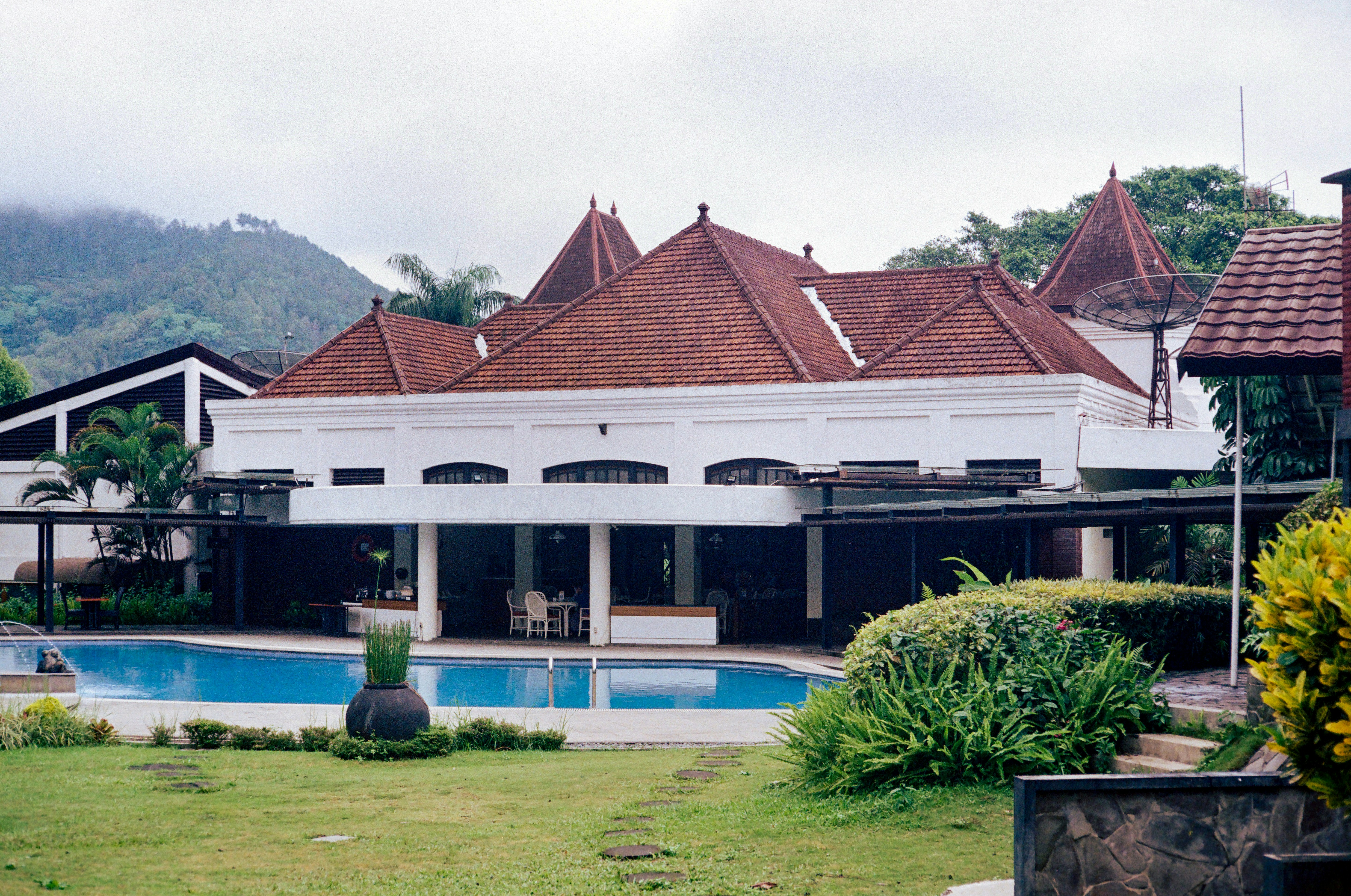A large white building with a swimming pool and mountains