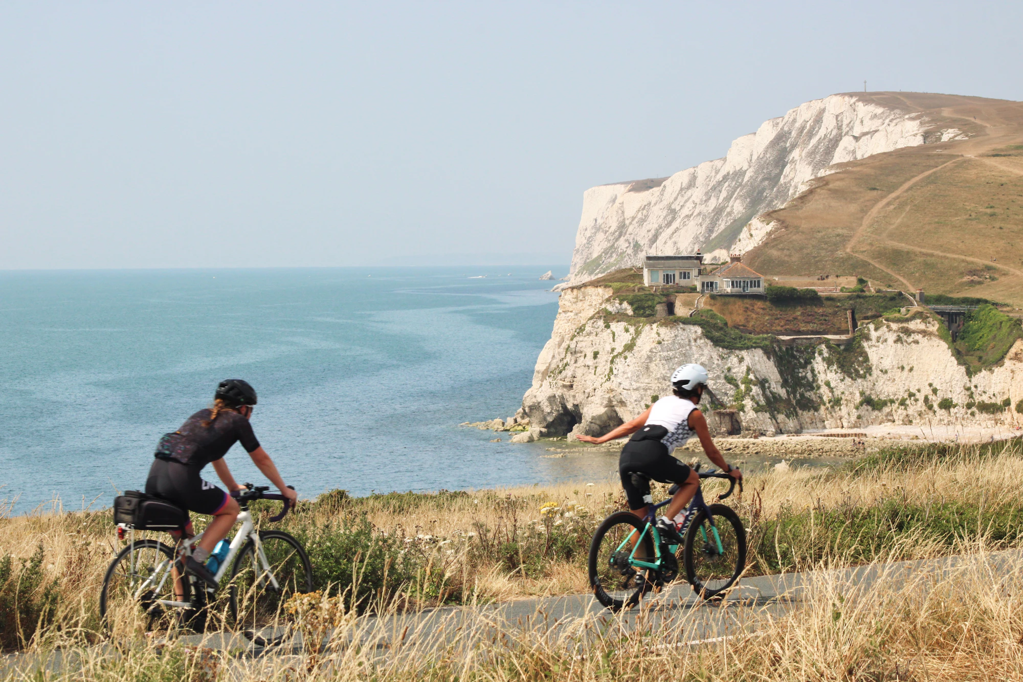 Two cyclists riding a cliff-top road above the sea on the Isle of Wight
