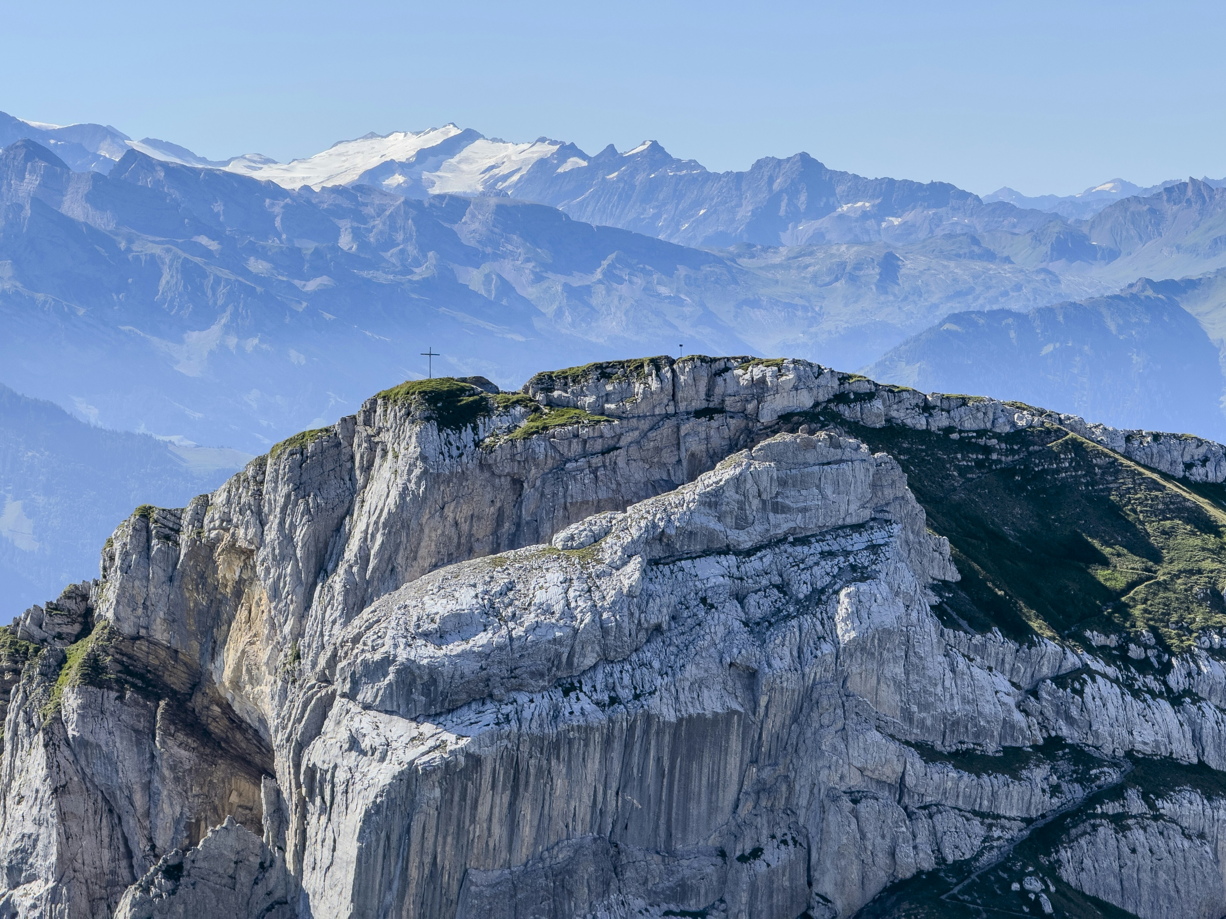 Rugged mountain peak with distant snow-capped mountains under clear sky