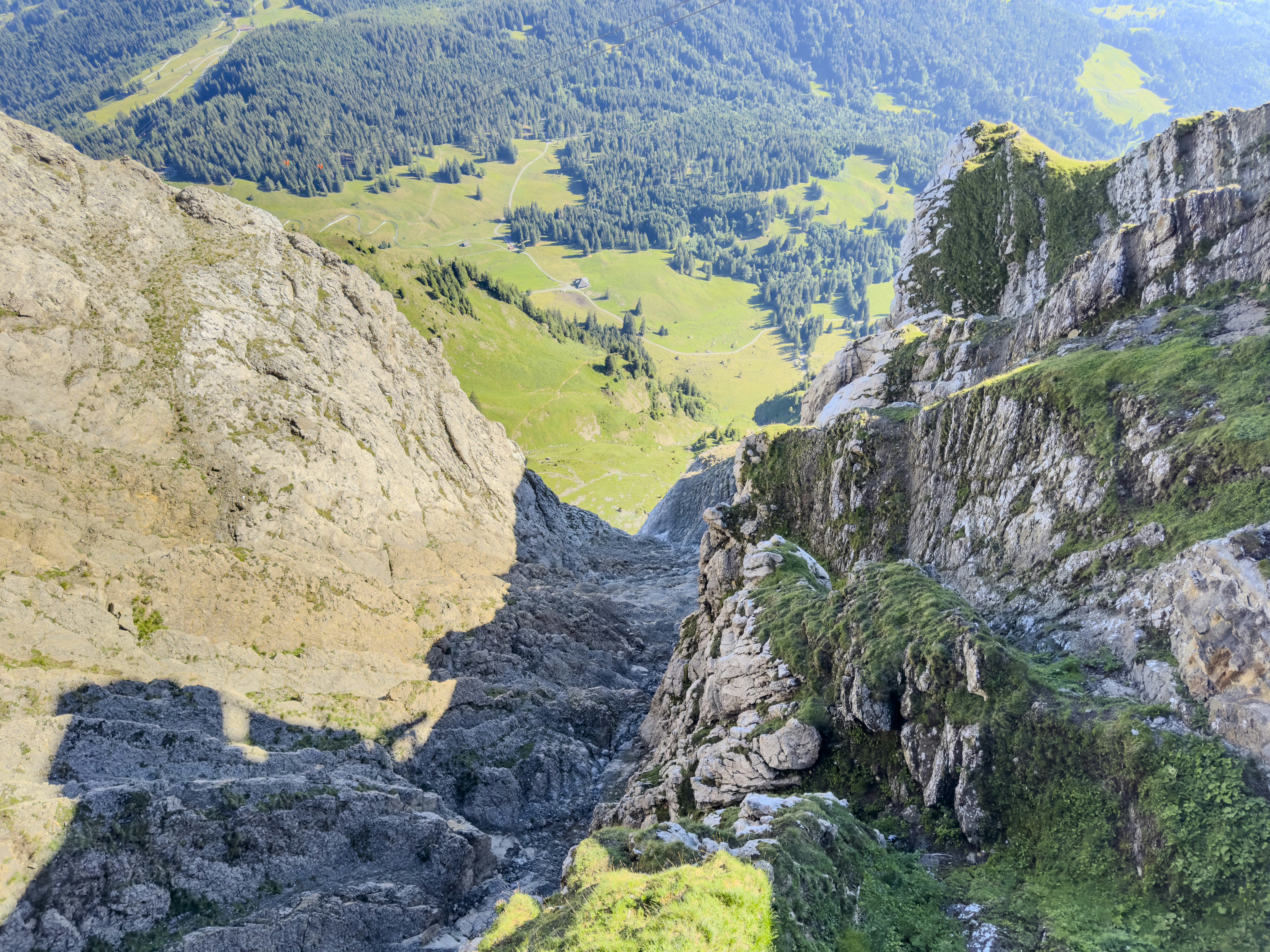 Steep rocky gorge between cliffs overlooking a green valley