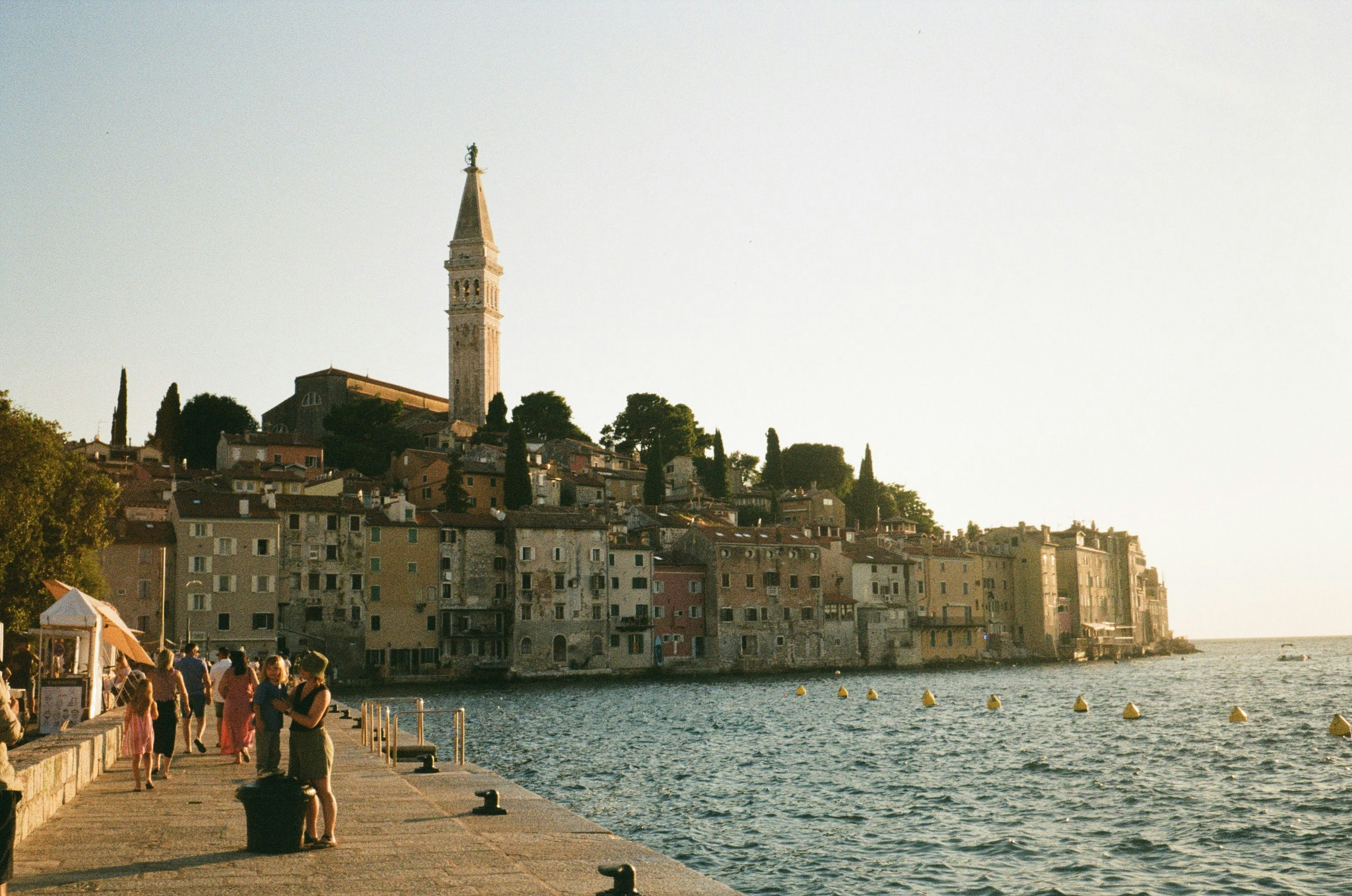 People strolling along a Croatian Adriatic waterfront promenade at sunset
