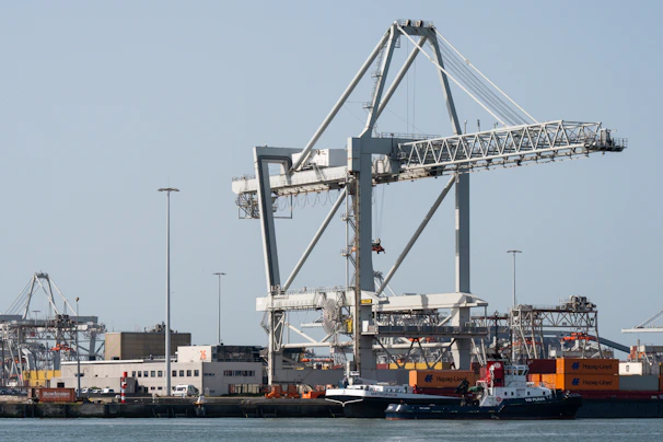 Large white gantry crane dominates a busy industrial port.